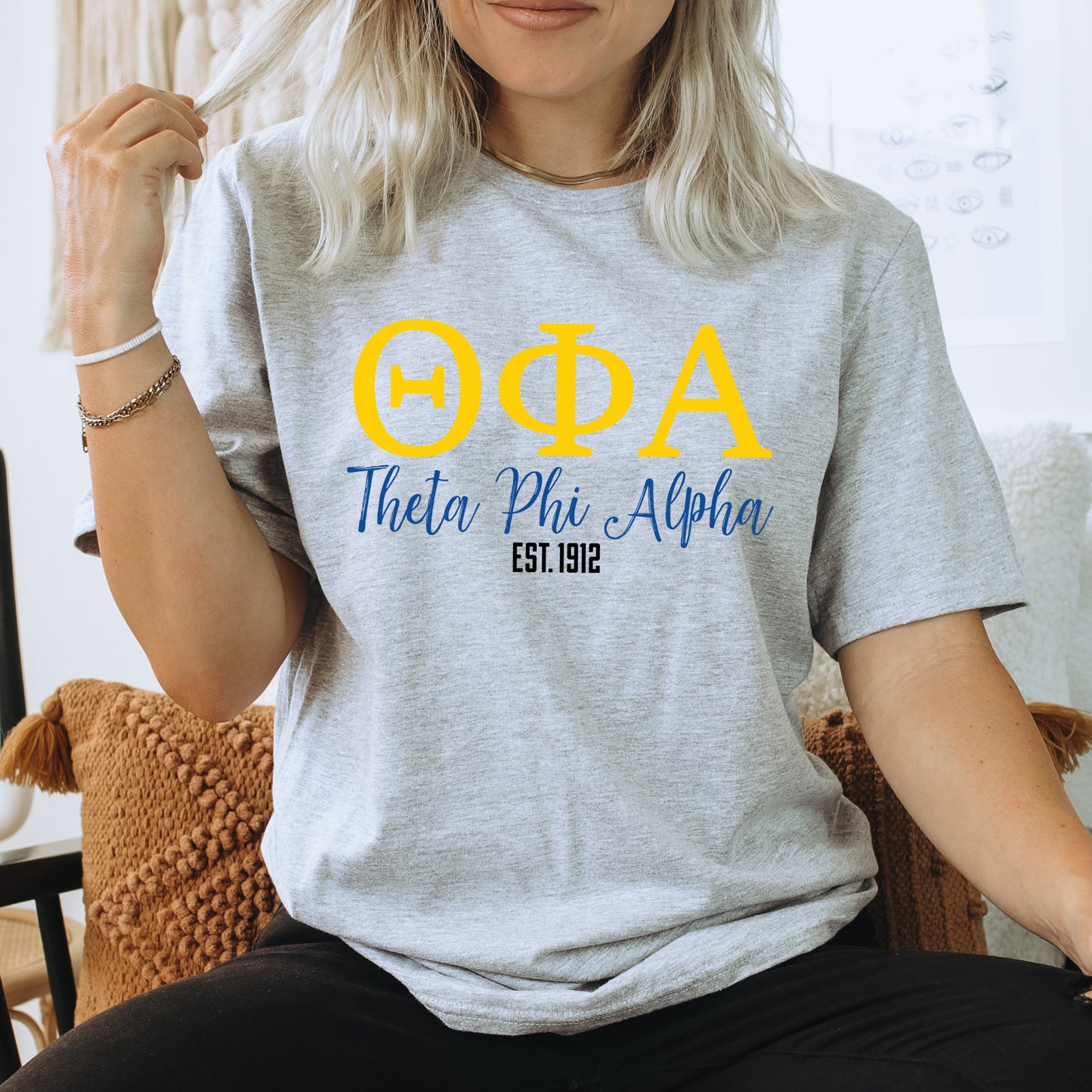 a woman sitting on a chair wearing a phi phi shirt