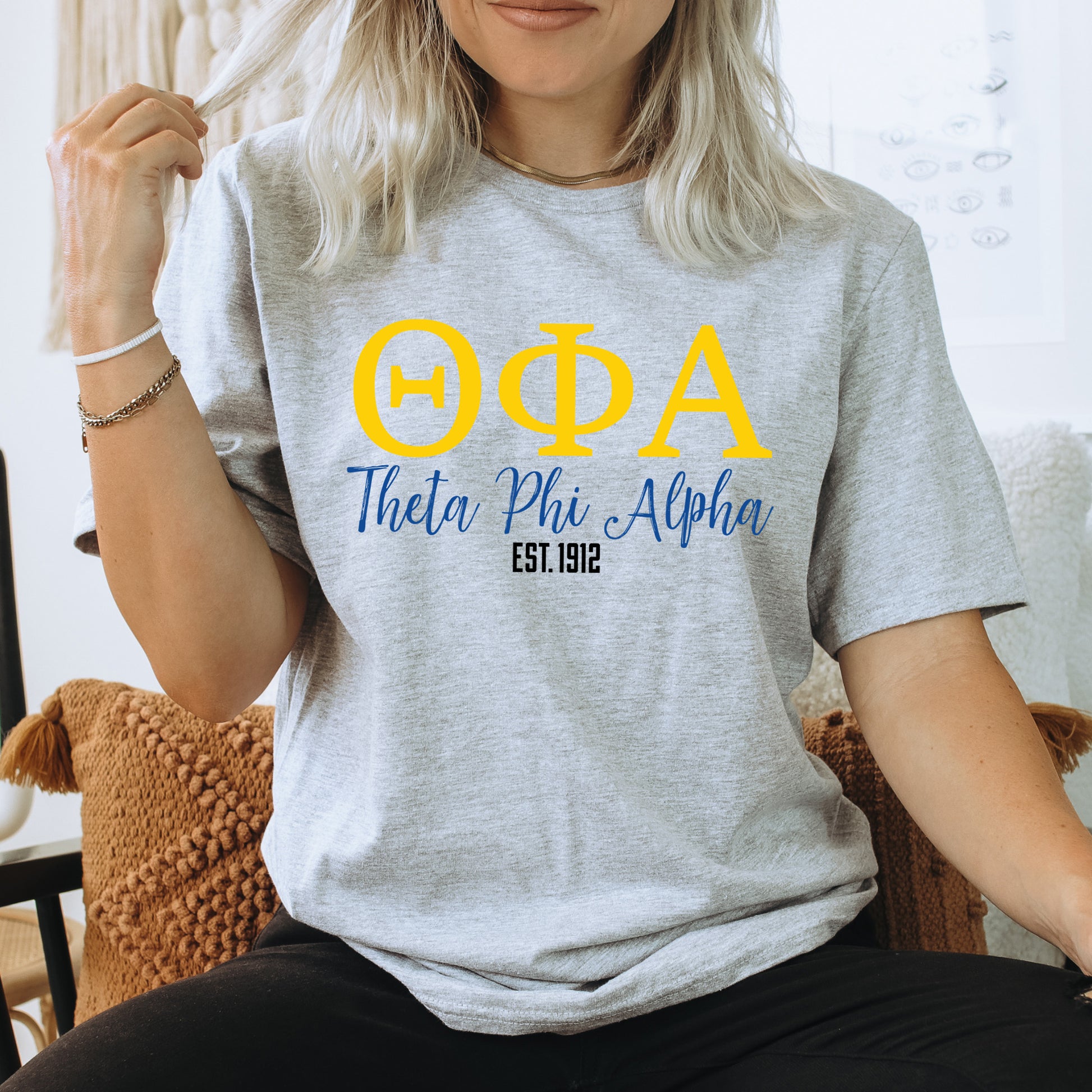 a woman sitting on a chair wearing a phi phi shirt