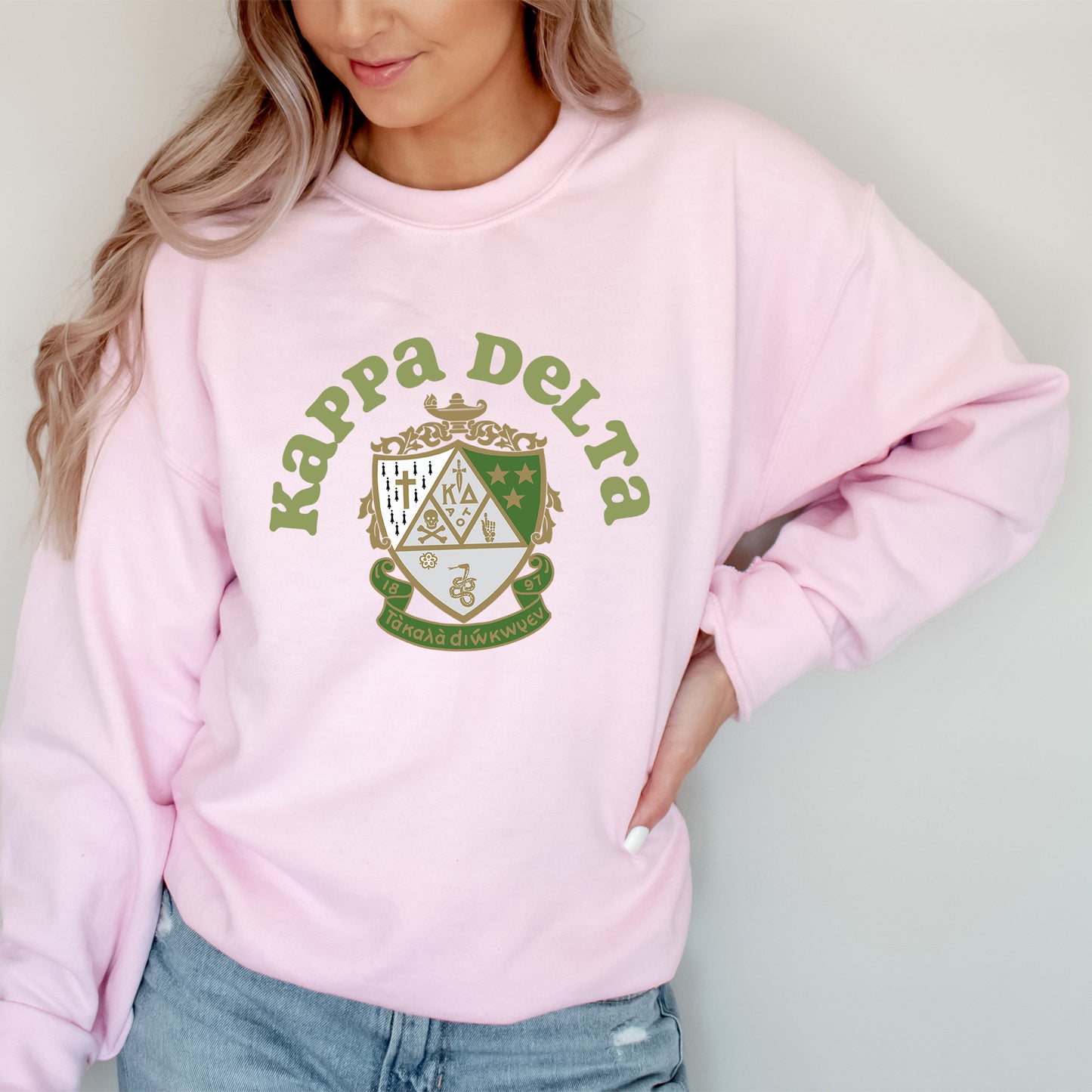a woman wearing a pink sweatshirt with a crest on it