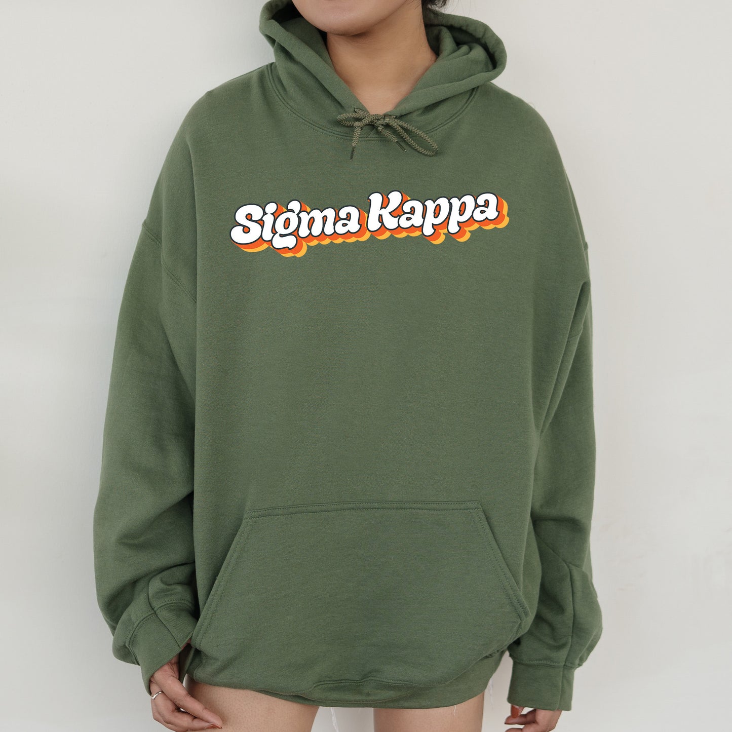 a person wearing a green hoodie with the word stigma kappa on it