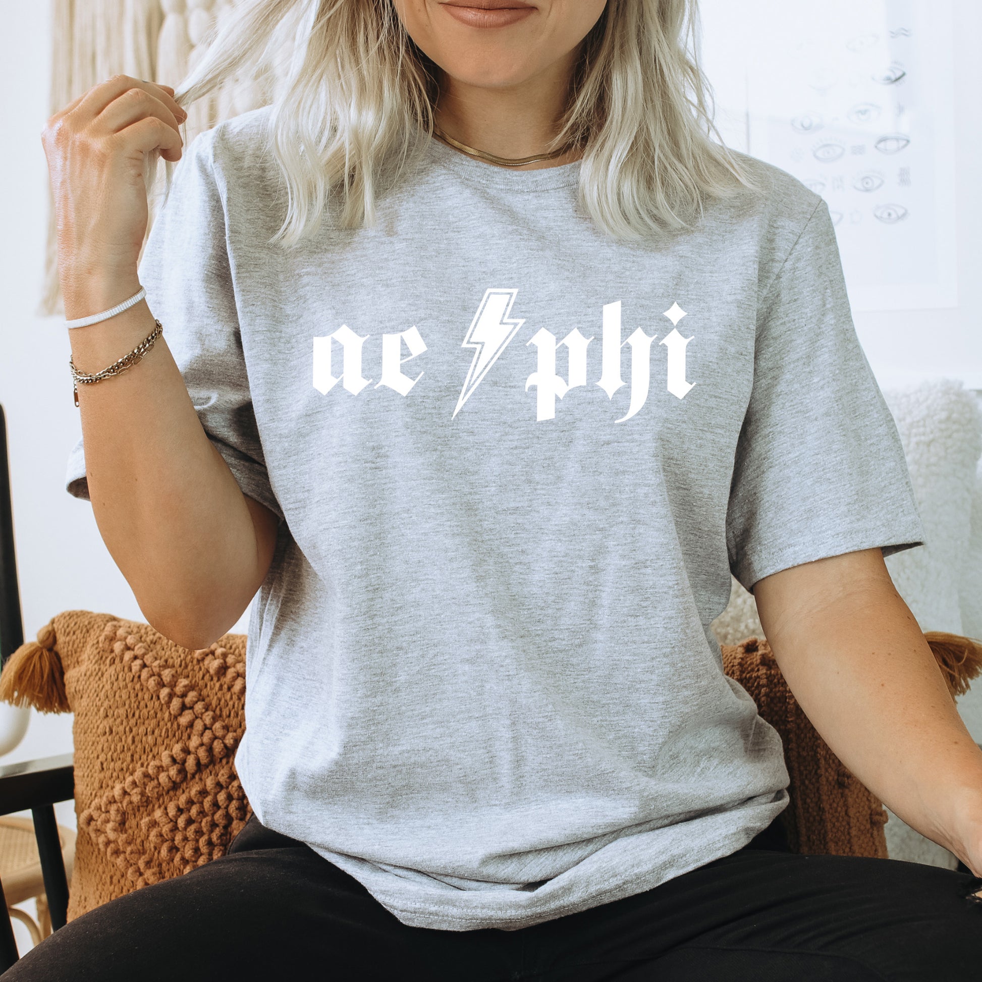 a woman sitting on a chair wearing a grey shirt with a lightning bolt on it