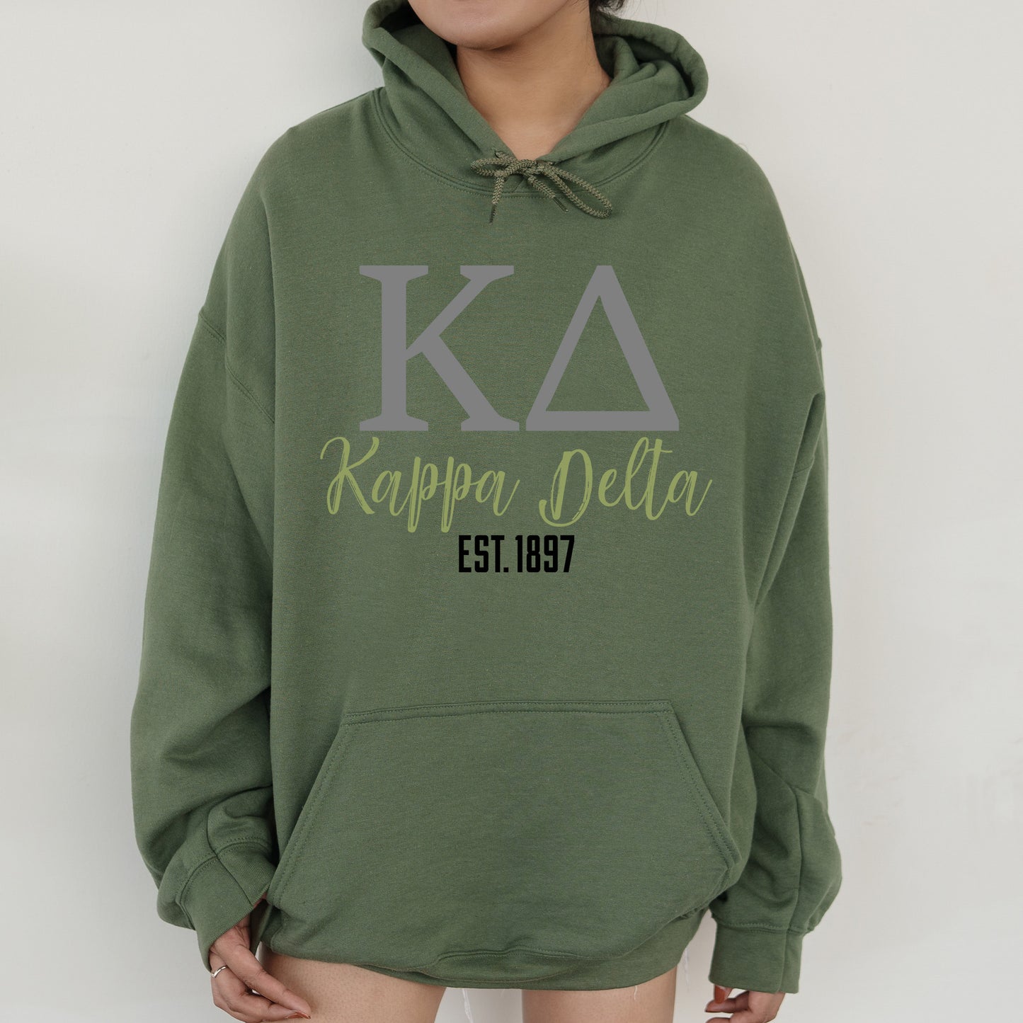 a woman wearing a green hoodie with the letters kapapaa delta on