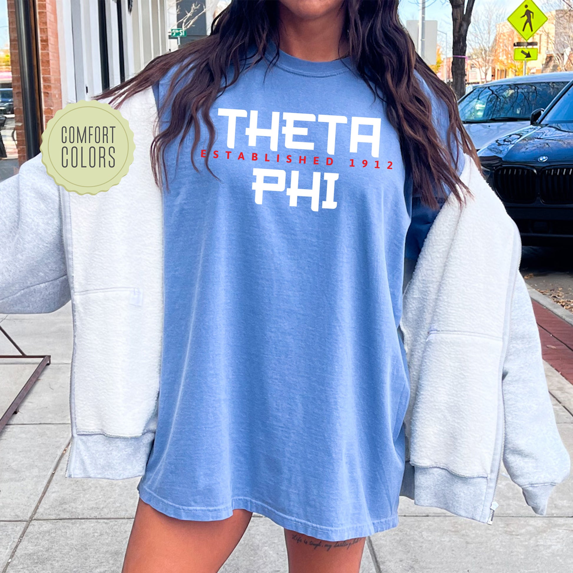 a woman standing on a sidewalk holding a blue shirt