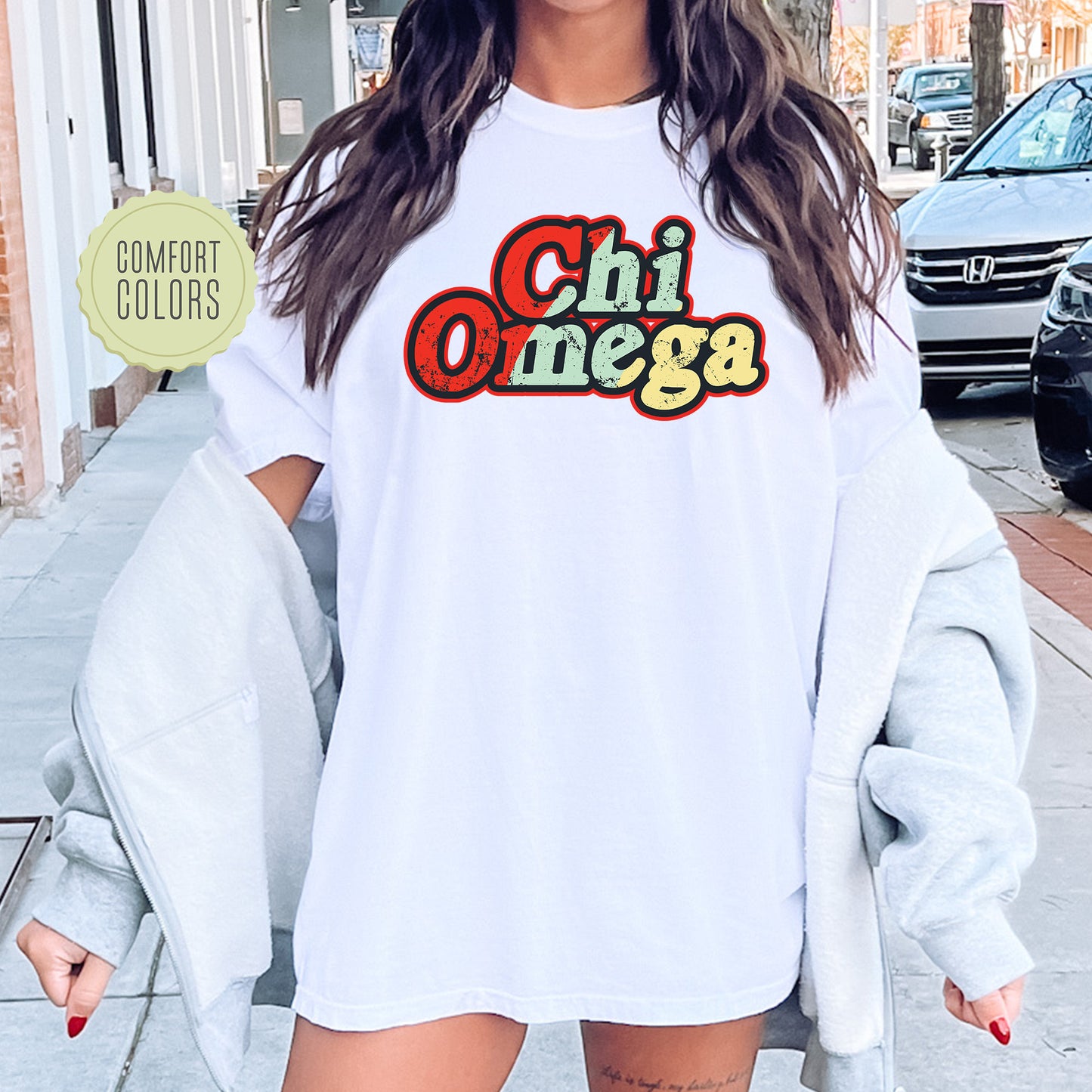 a woman wearing a white shirt with the word chi omega on it