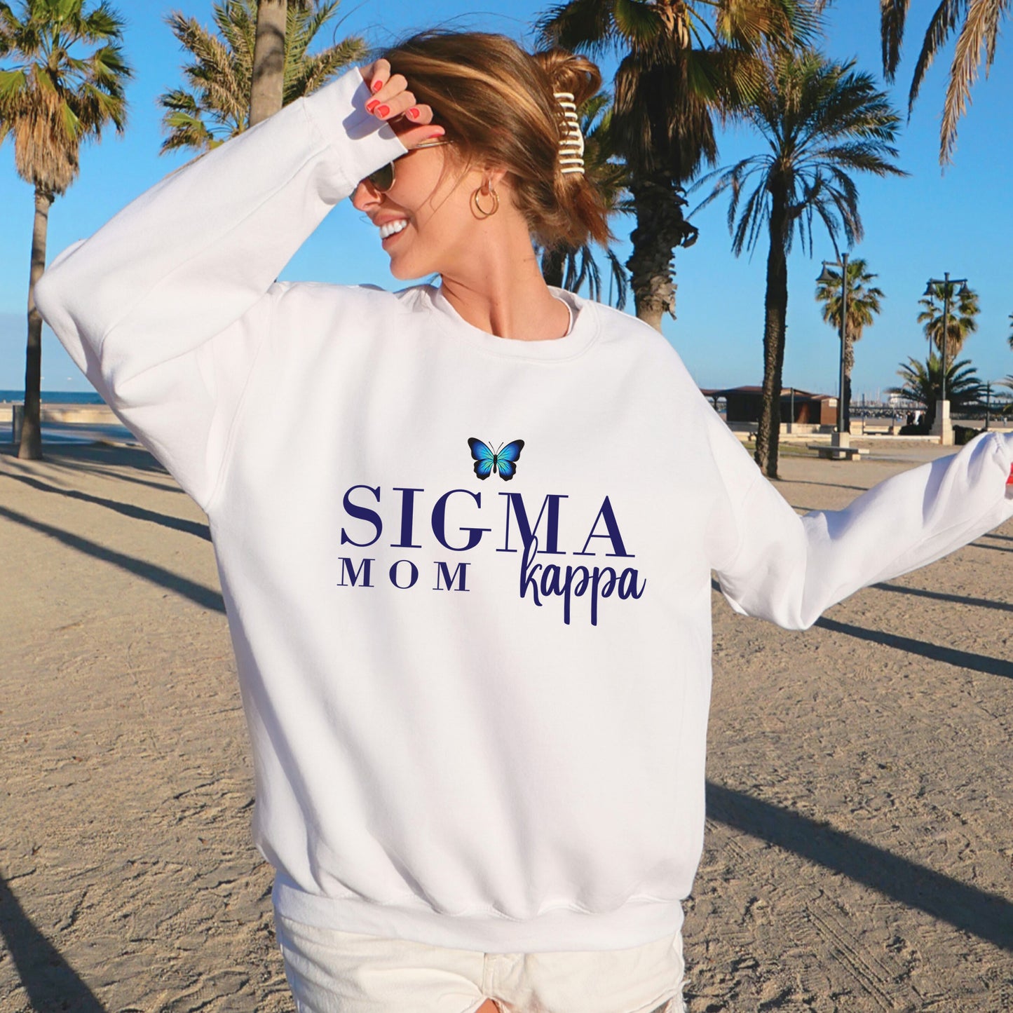 a woman standing on a beach wearing a white sweatshirt
