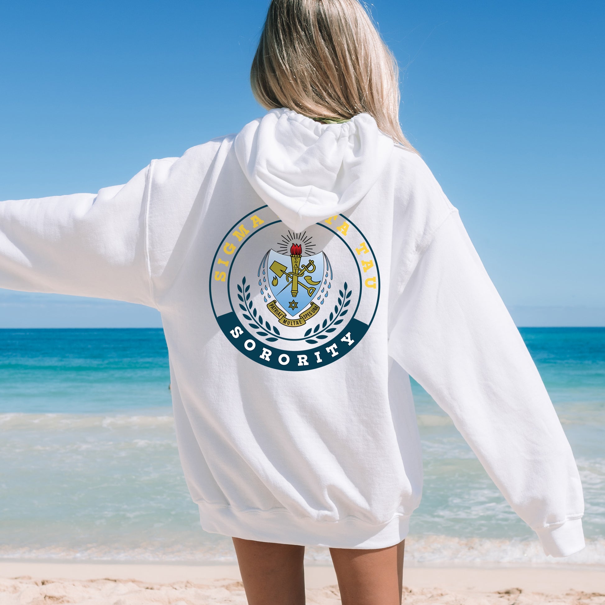 a woman standing on a beach wearing a white hoodie