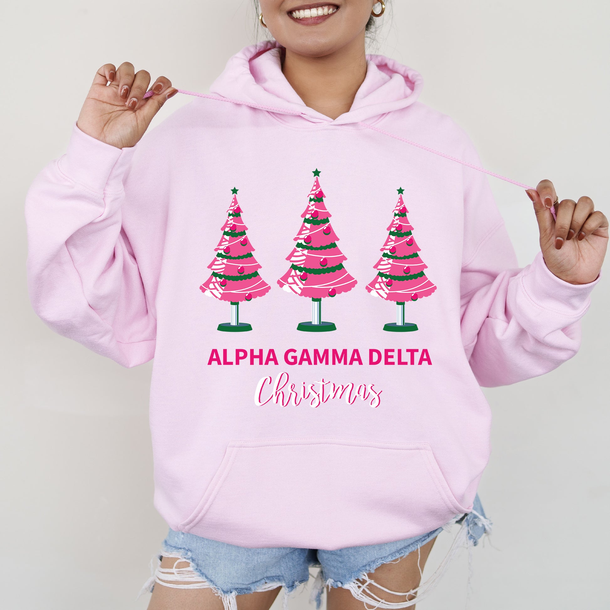 a woman wearing a pink hoodie with christmas trees on it