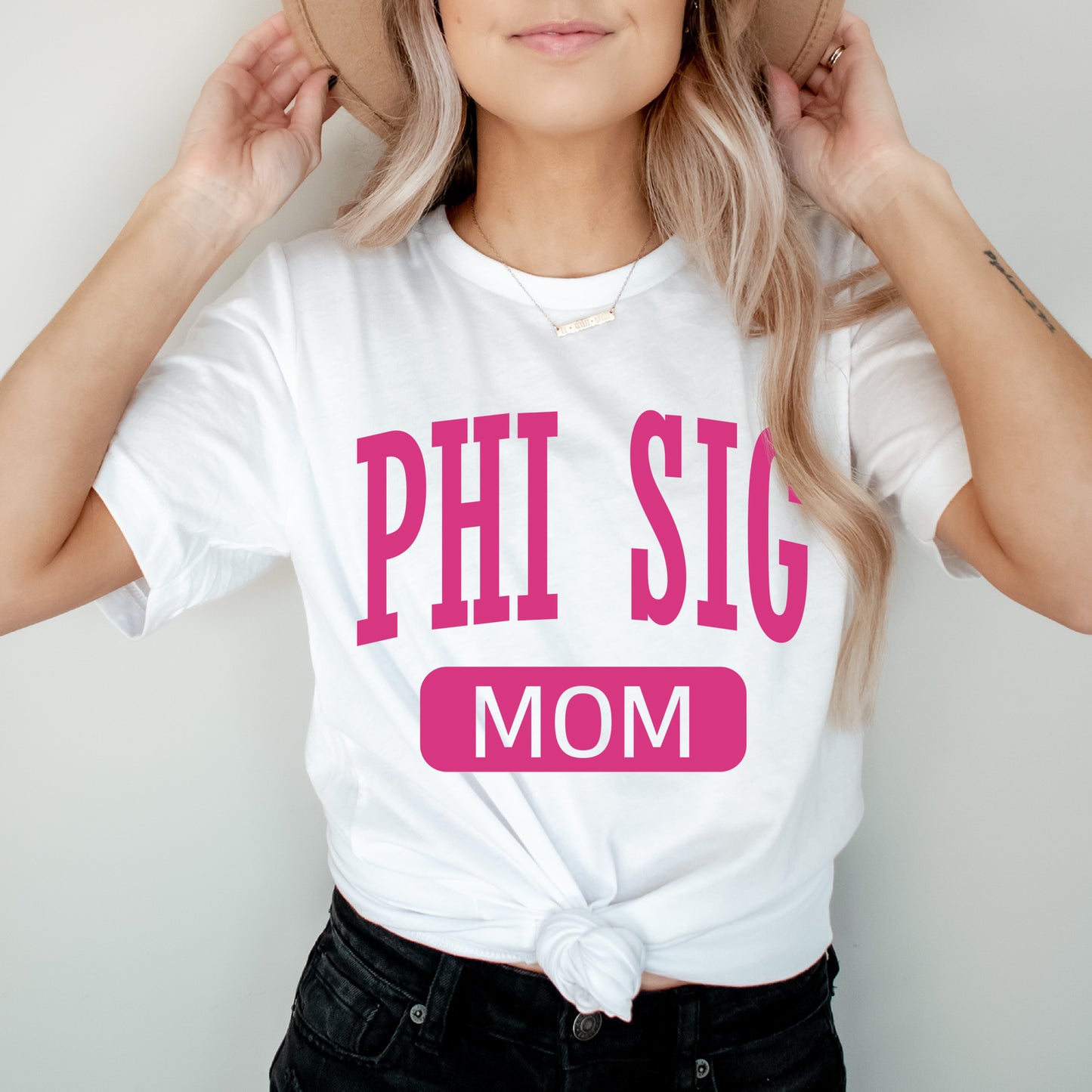 a woman wearing a hat and a shirt that says phi sig mom
