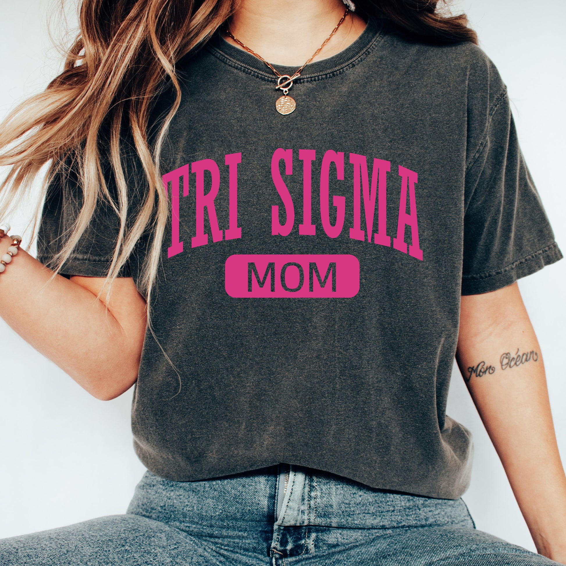 a woman sitting on a chair wearing a shirt that says tri sigma mom
