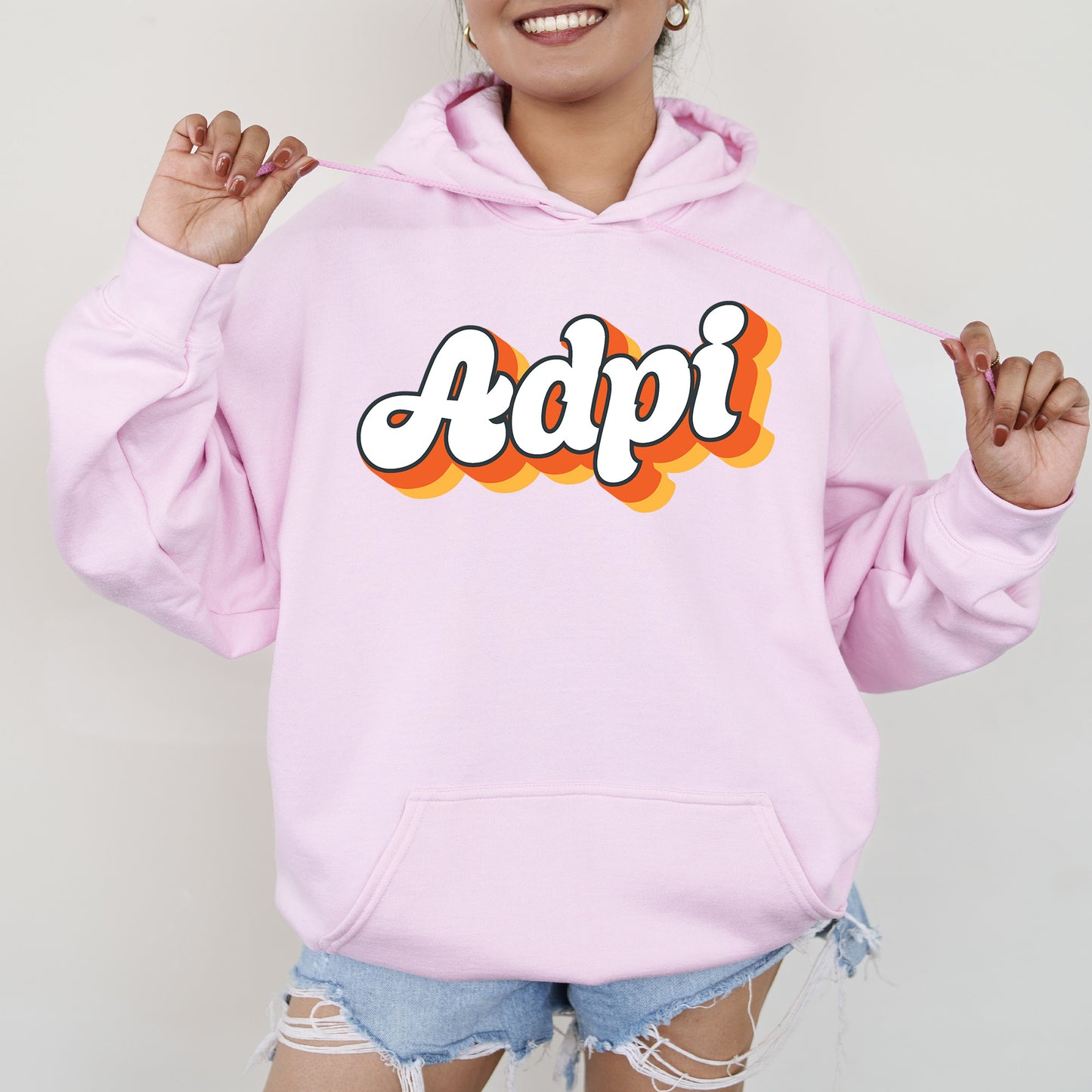 a woman wearing a pink hoodie with the word adpi printed on it
