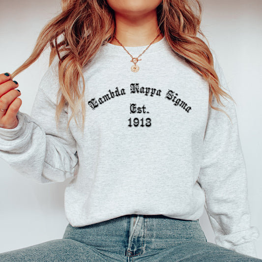 a woman wearing a sweatshirt and jeans holding a cigarette