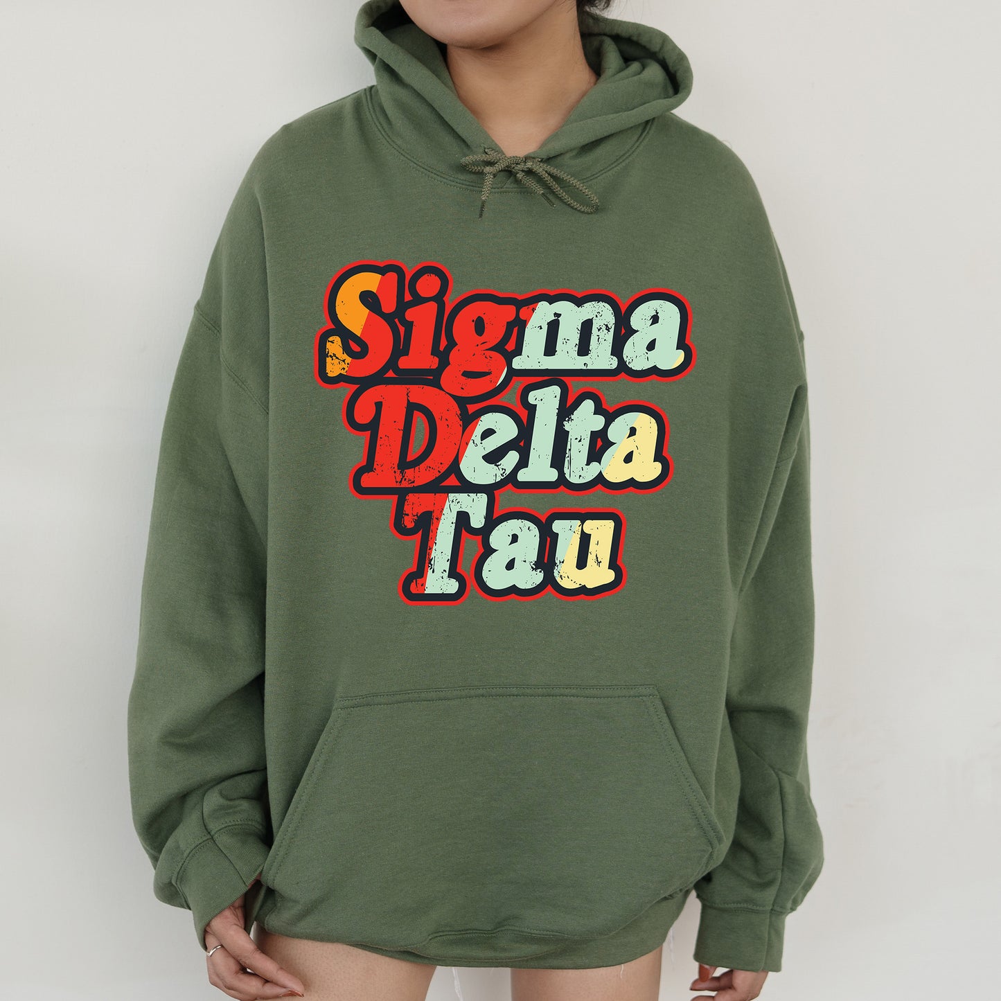 a woman wearing a green hoodie with the words stigmaa delta tau on it