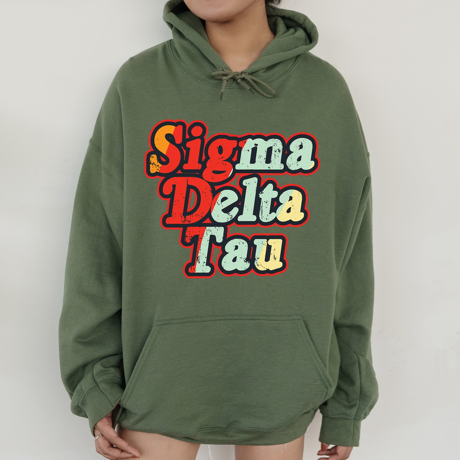 a woman wearing a green hoodie with the words stigmaa delta tau on it
