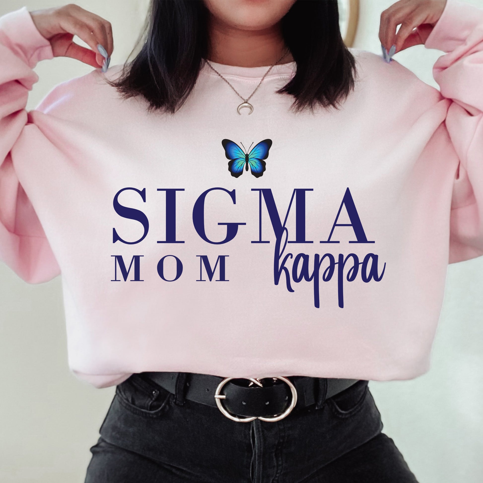 a woman holding a pink sweater with a butterfly on it
