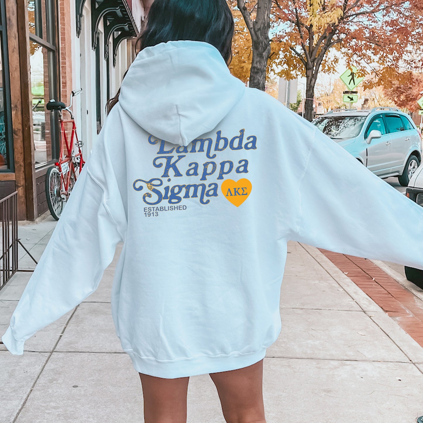 a woman in a white hoodie walking down a sidewalk