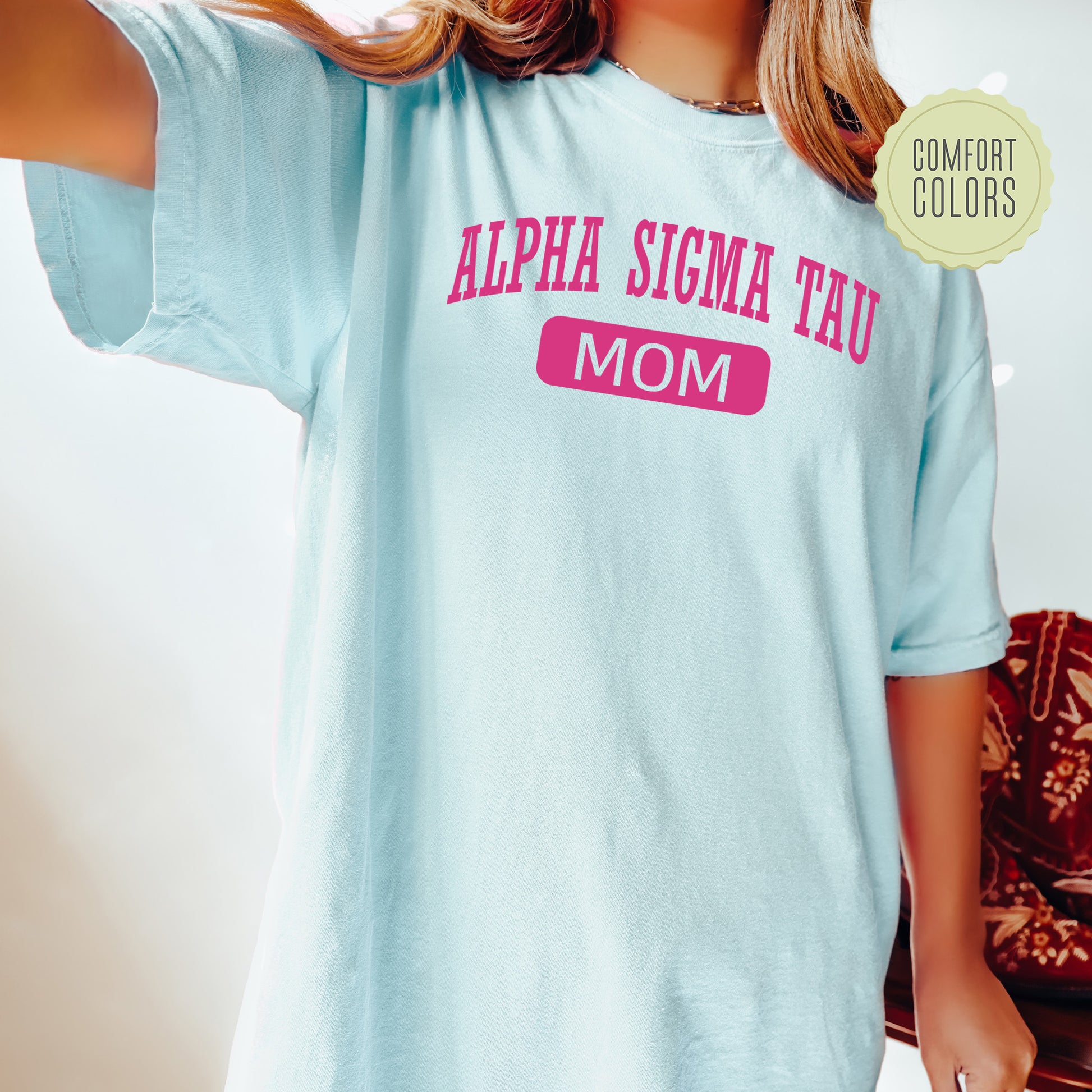 a woman wearing a light blue shirt with pink letters on it