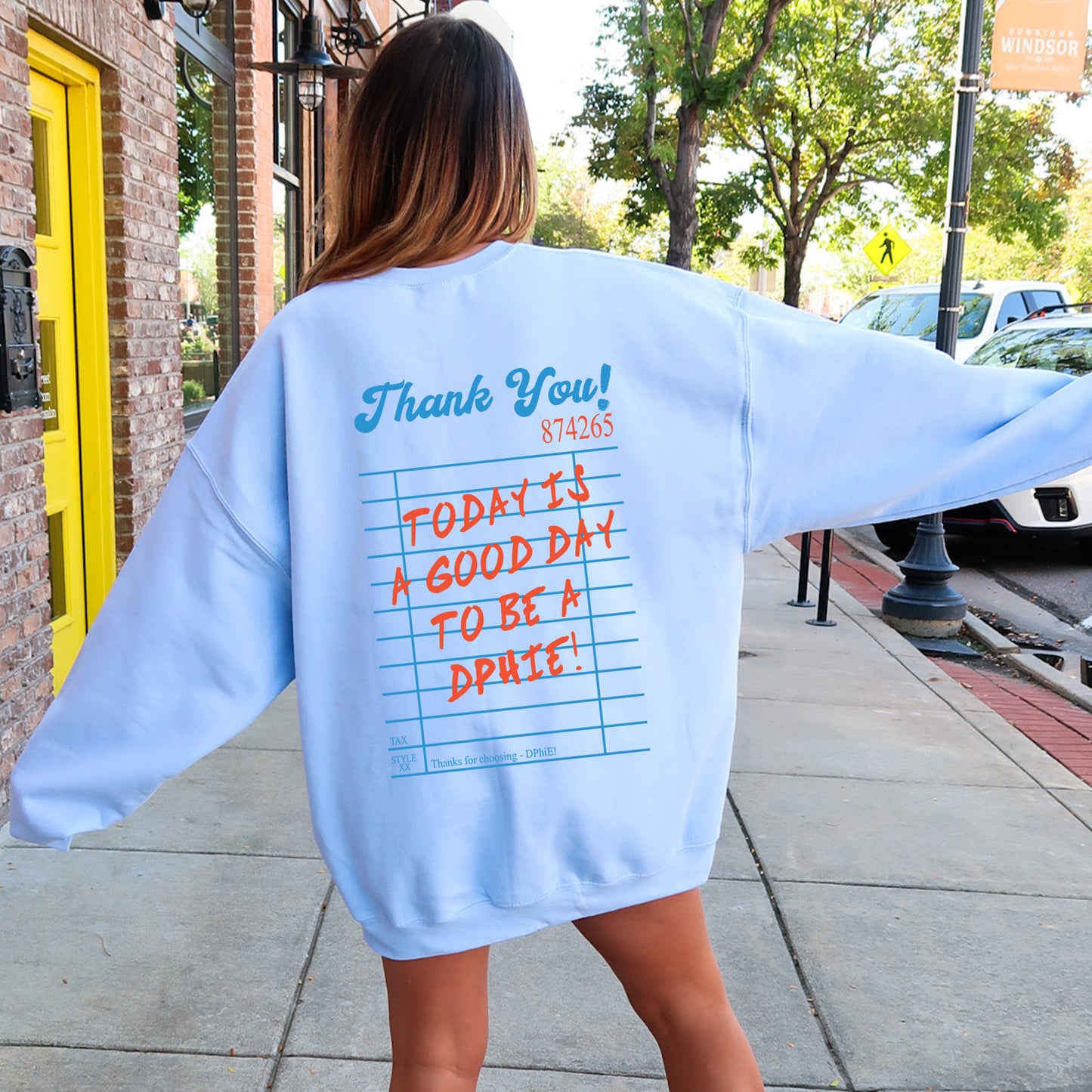 a woman in a blue sweatshirt is walking down the sidewalk
