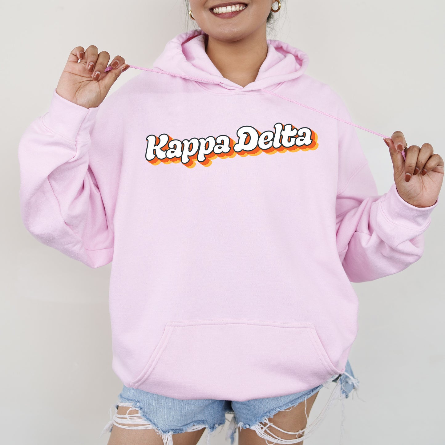 a woman wearing a pink hoodie with the words kapppa delta on it