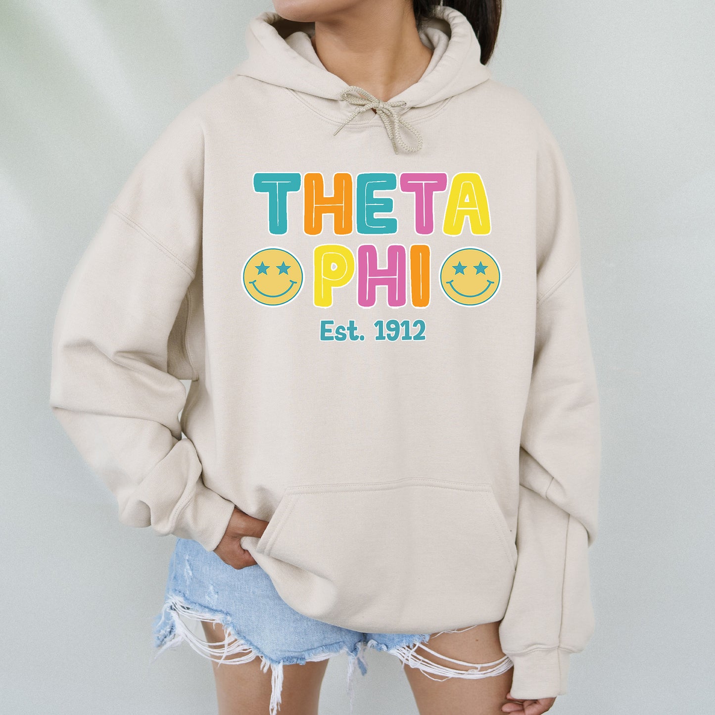 a woman wearing a sweatshirt that says theta phi est 1911
