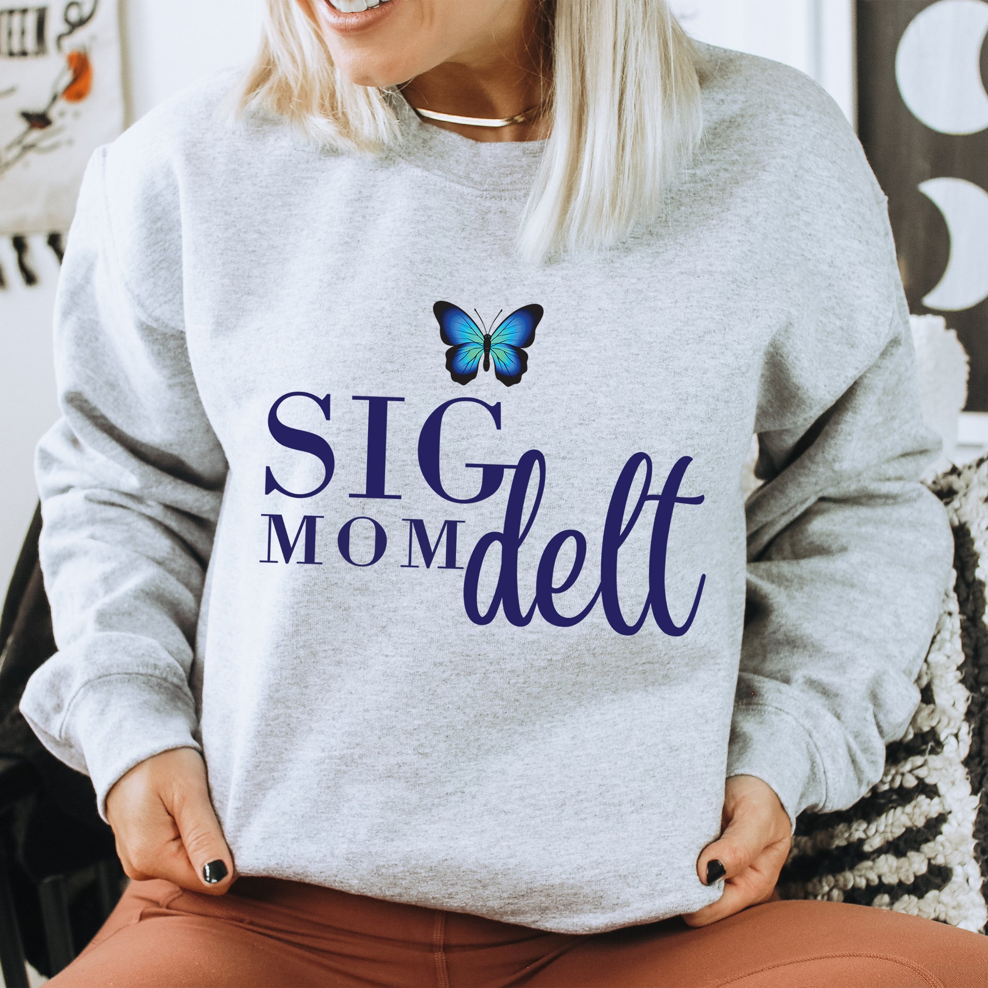 a woman sitting on a chair with a butterfly on her sweatshirt