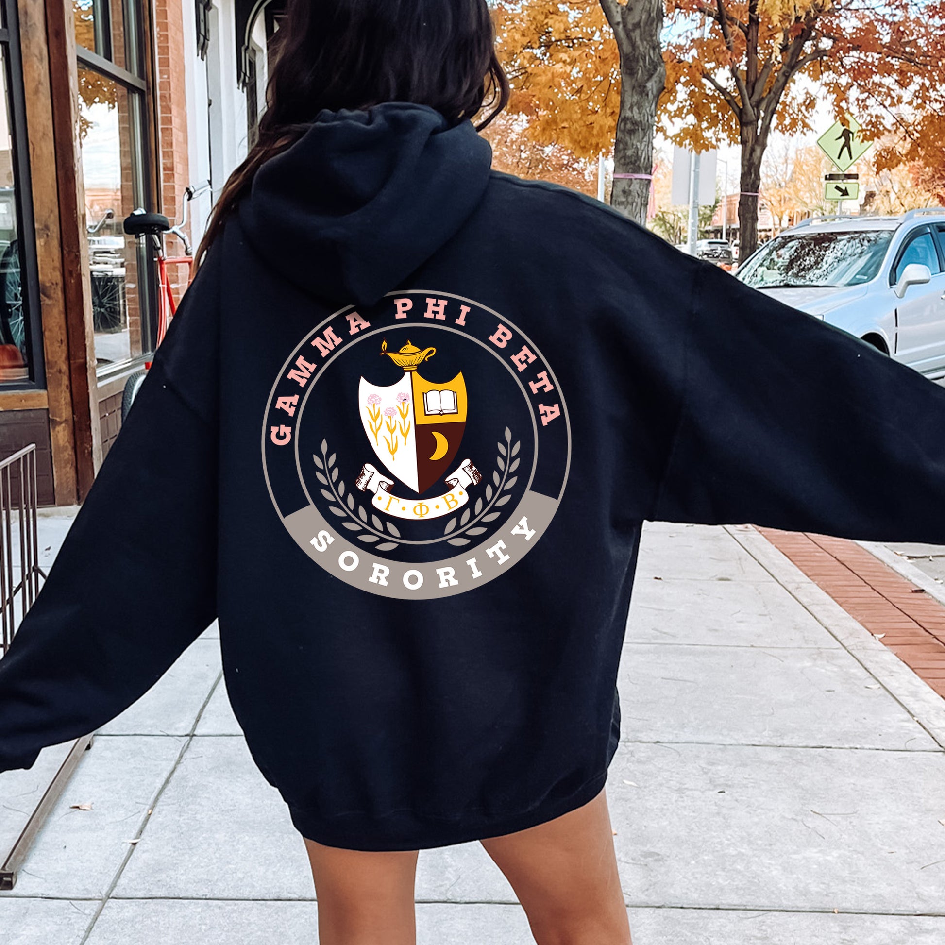 a woman walking down a sidewalk with a hoodie on