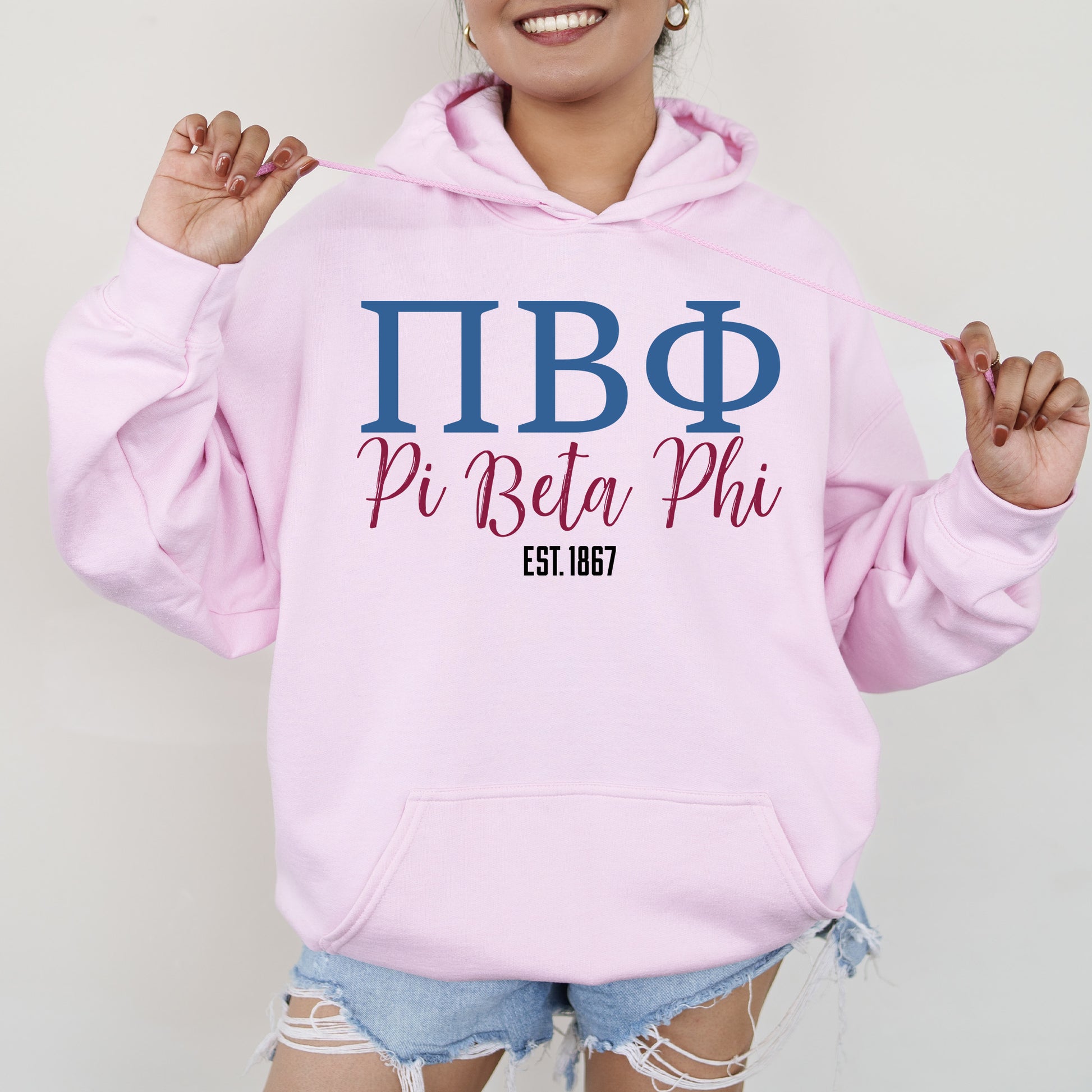 a woman wearing a pink hoodie and ripped shorts