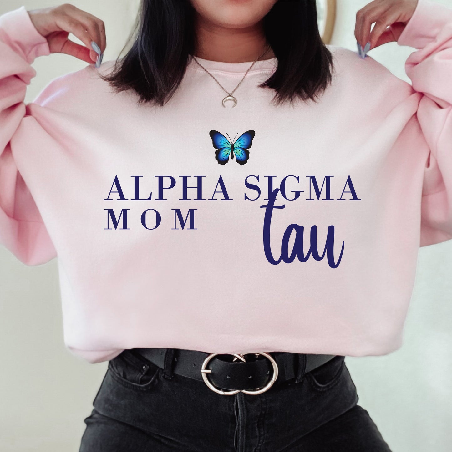 a woman holding a pink sweatshirt with a butterfly on it