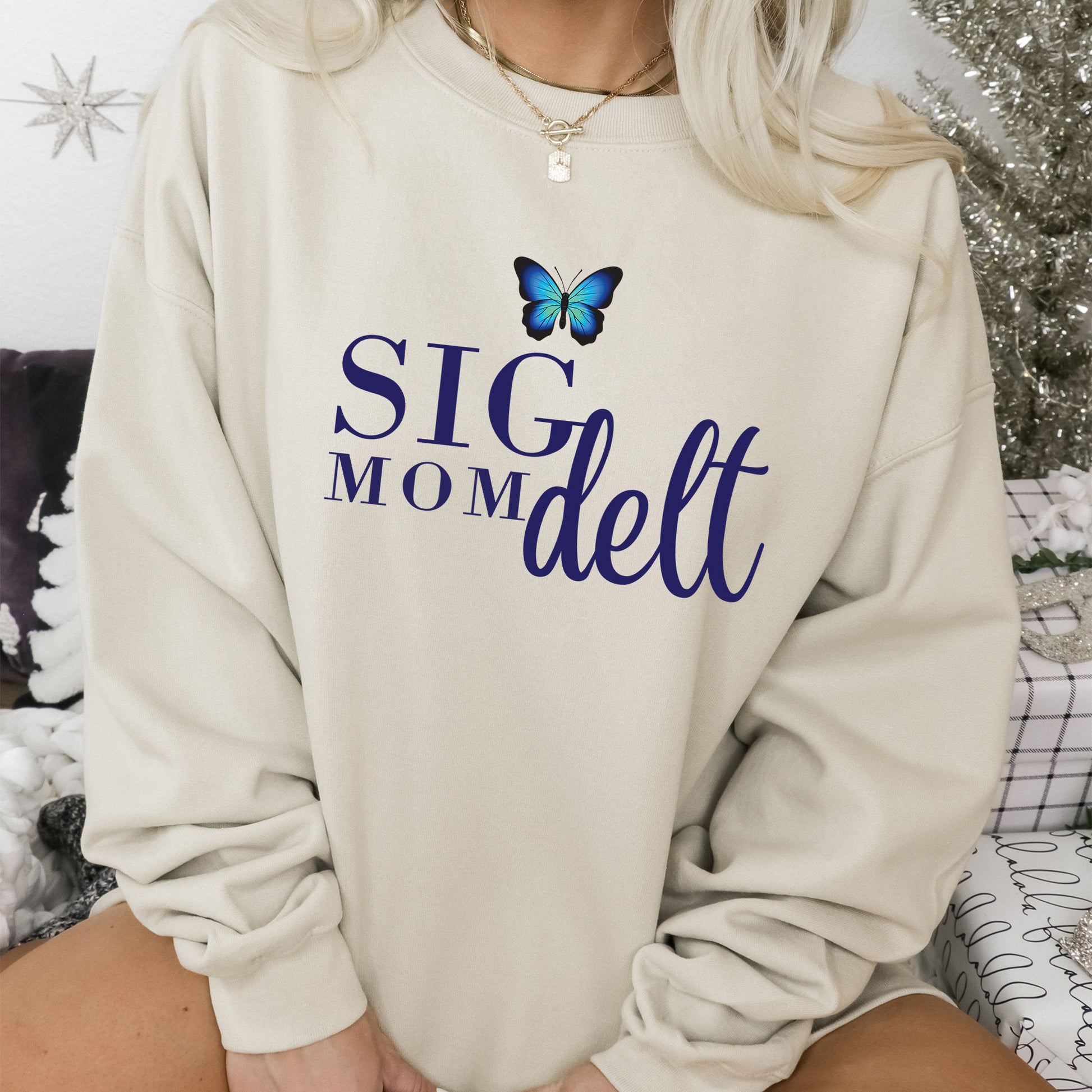 a woman sitting on a bed wearing a sweatshirt with a butterfly on it