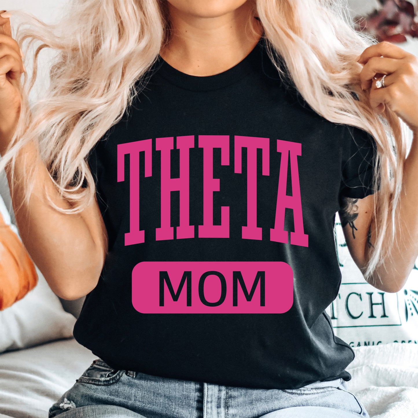 a woman with blonde hair wearing a black t - shirt that says theta mom