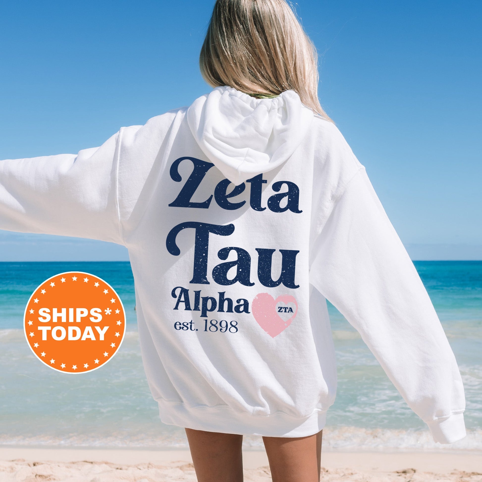 a woman standing on a beach wearing a white hoodie