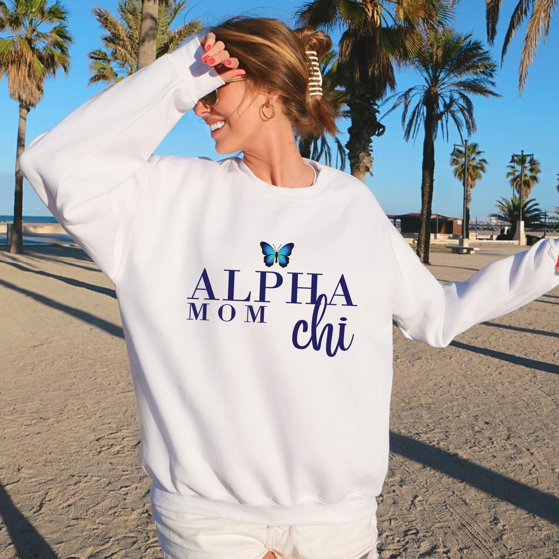 a woman standing on a beach wearing a white sweatshirt