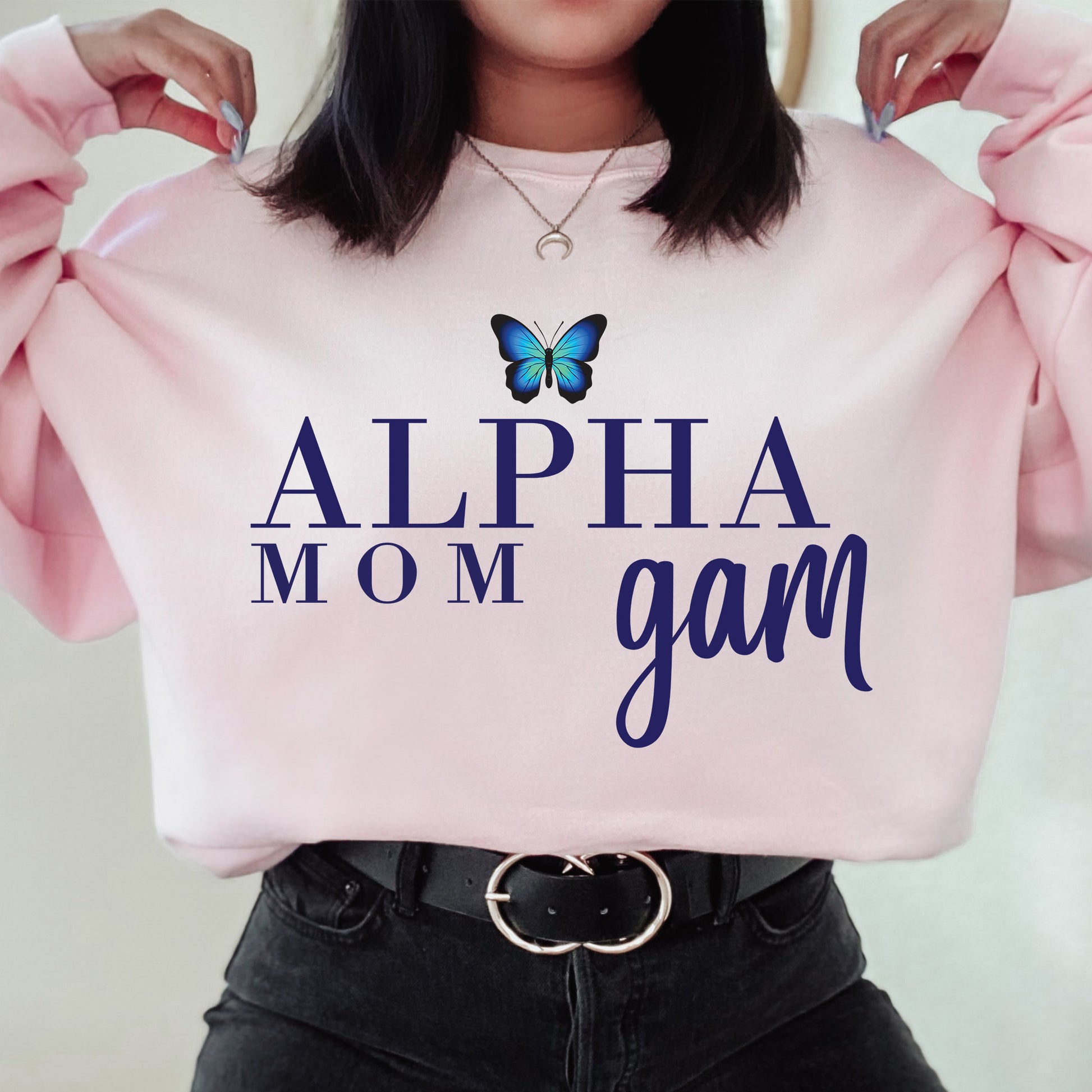 a woman holding a pink sweatshirt with a butterfly on it