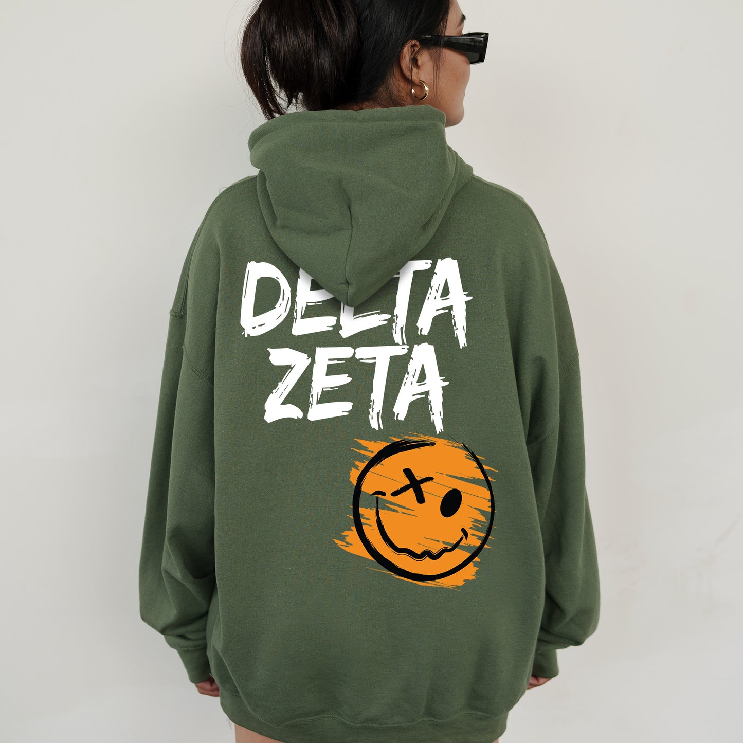 a woman wearing a green hoodie with the words delta zeta on it