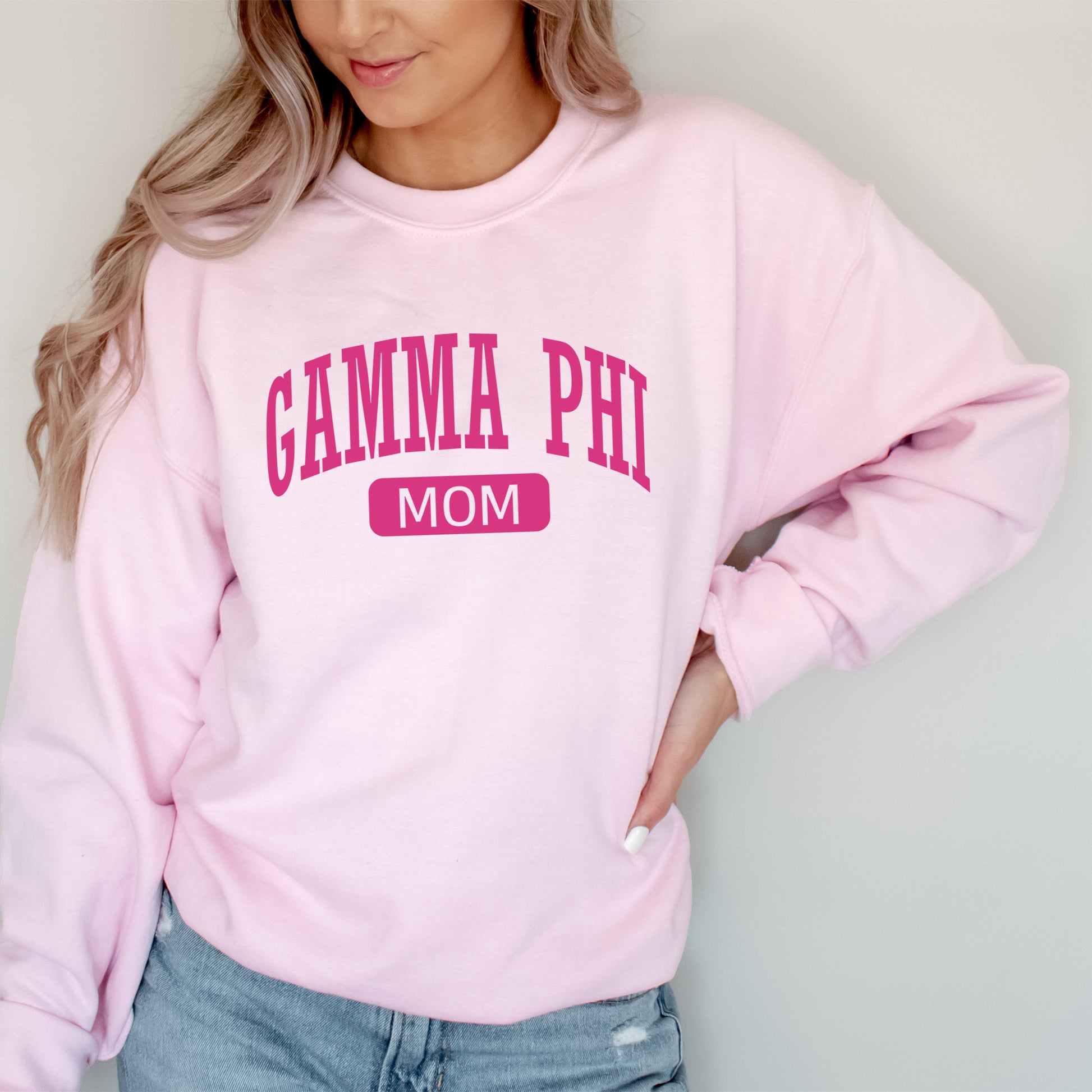 a woman wearing a pink sweatshirt with the word gama phi on it