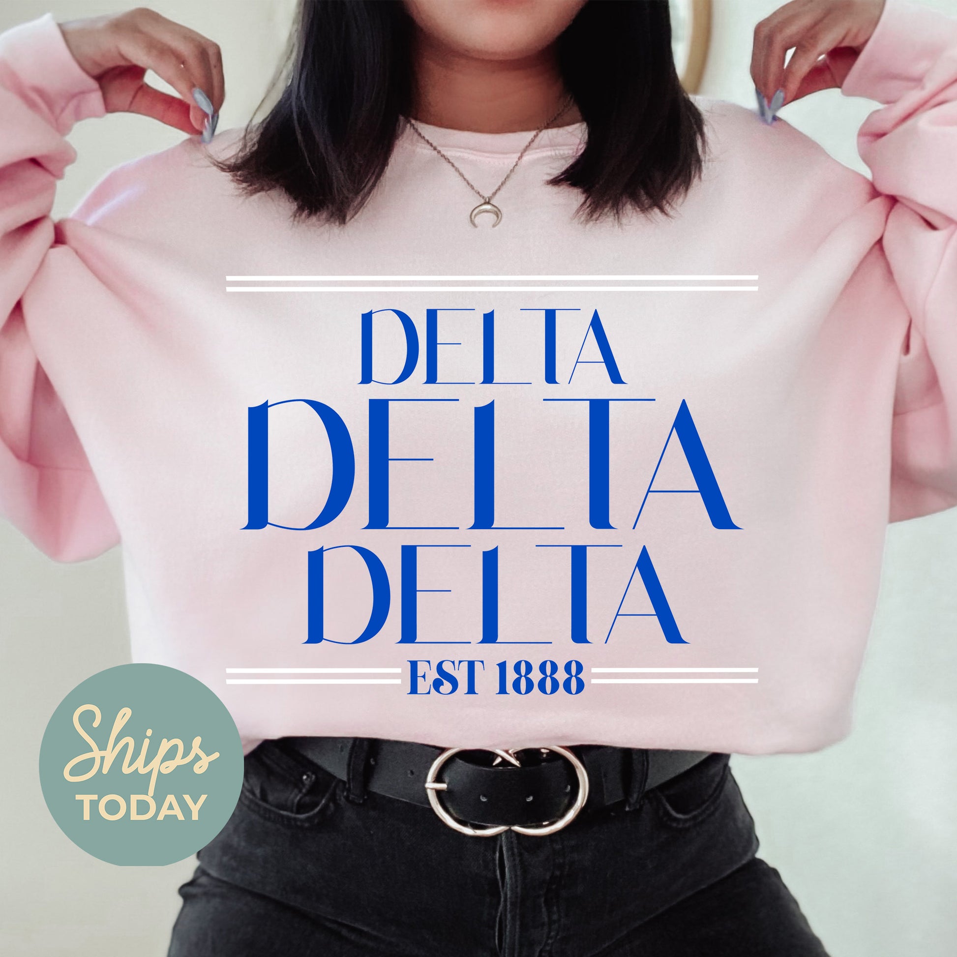 a woman holding a pink shirt with the words delta delta on it