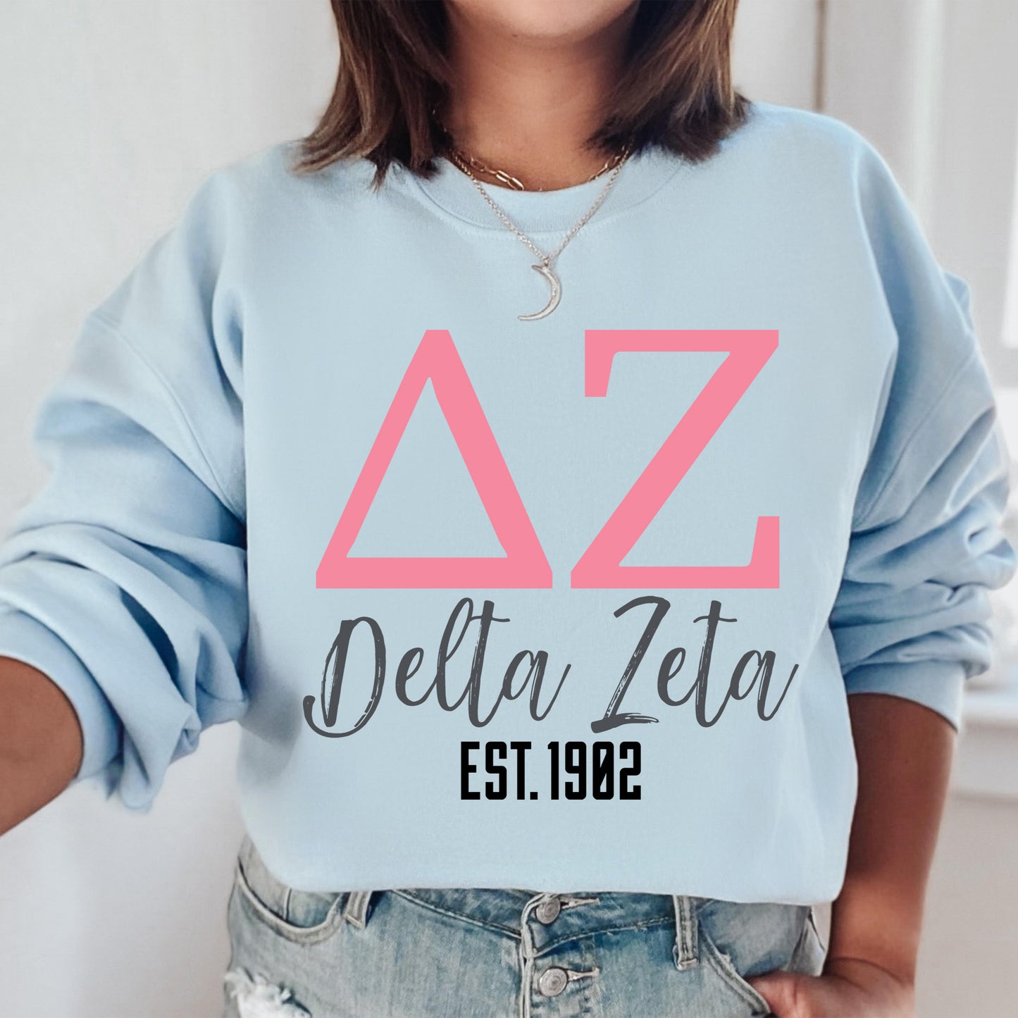 a woman wearing a blue sweatshirt with pink letters on it