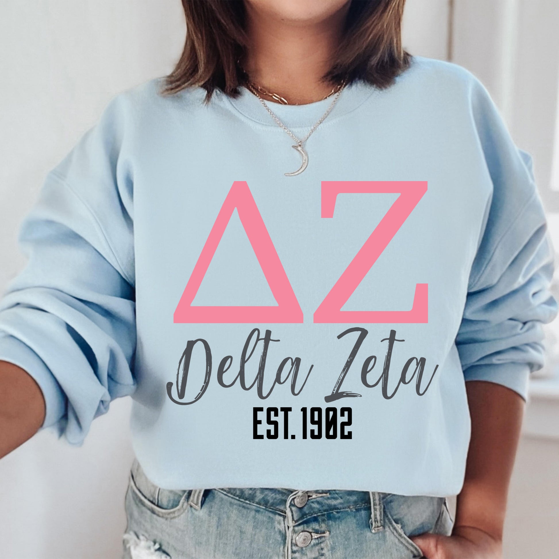 a woman wearing a blue sweatshirt with pink letters on it