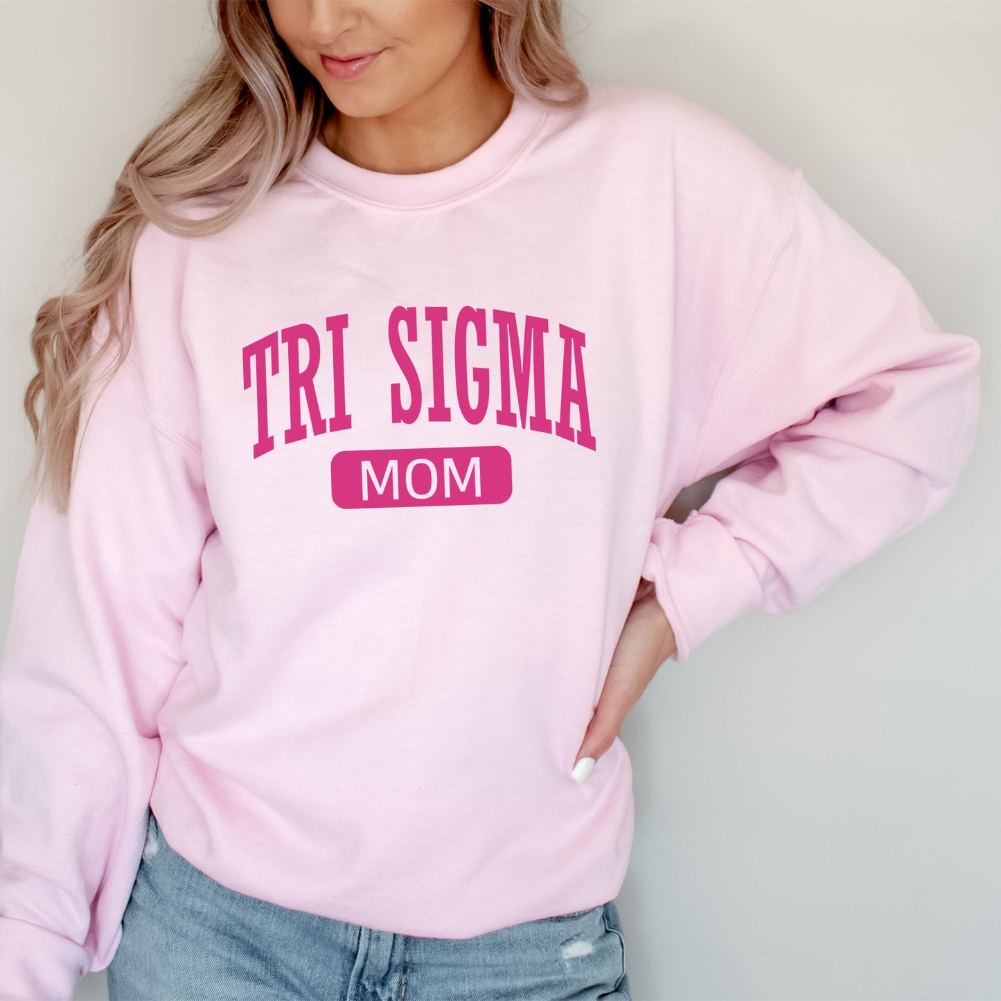 a woman wearing a pink sweatshirt with the word tri stigma on it