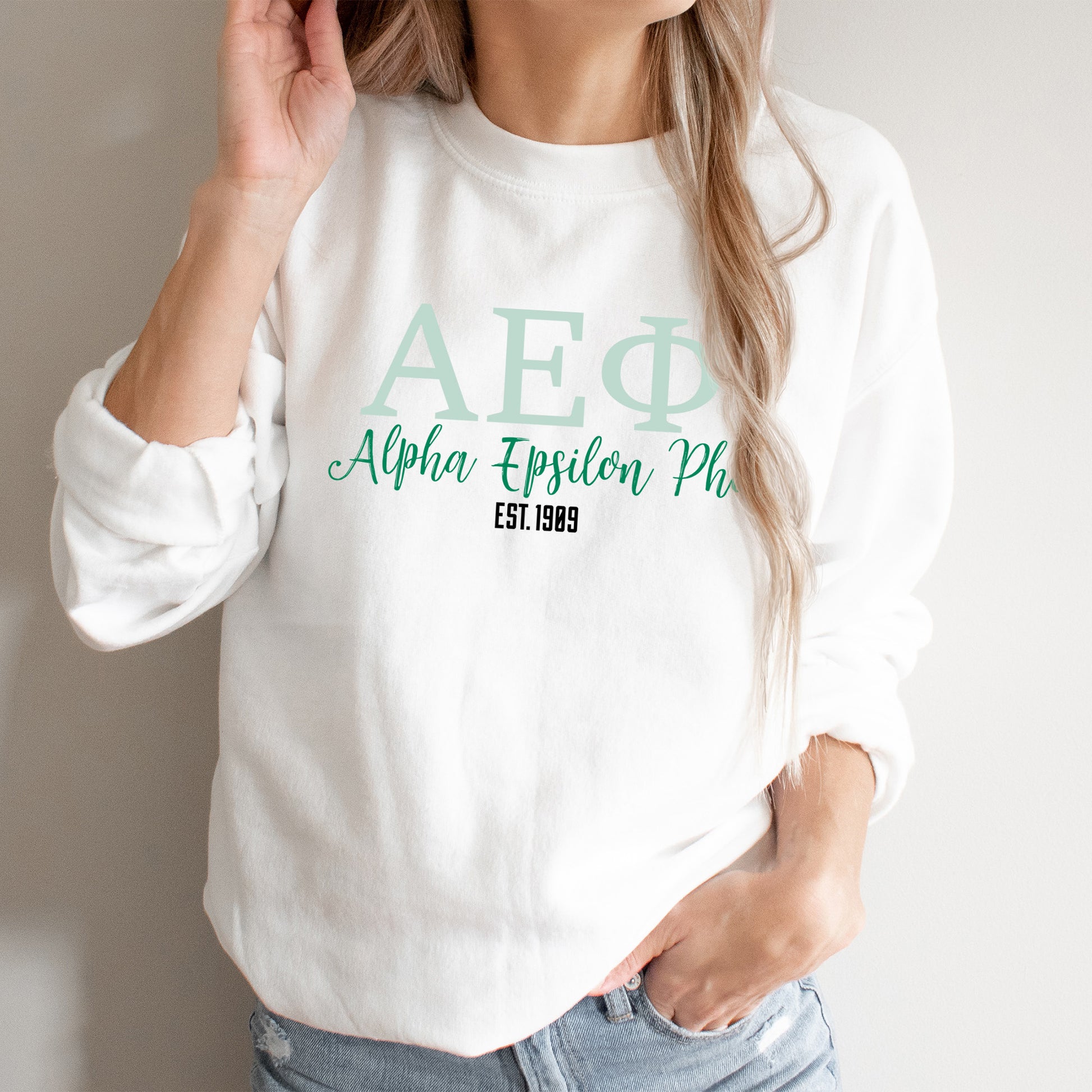 a woman wearing a white sweatshirt with a green afq logo on it