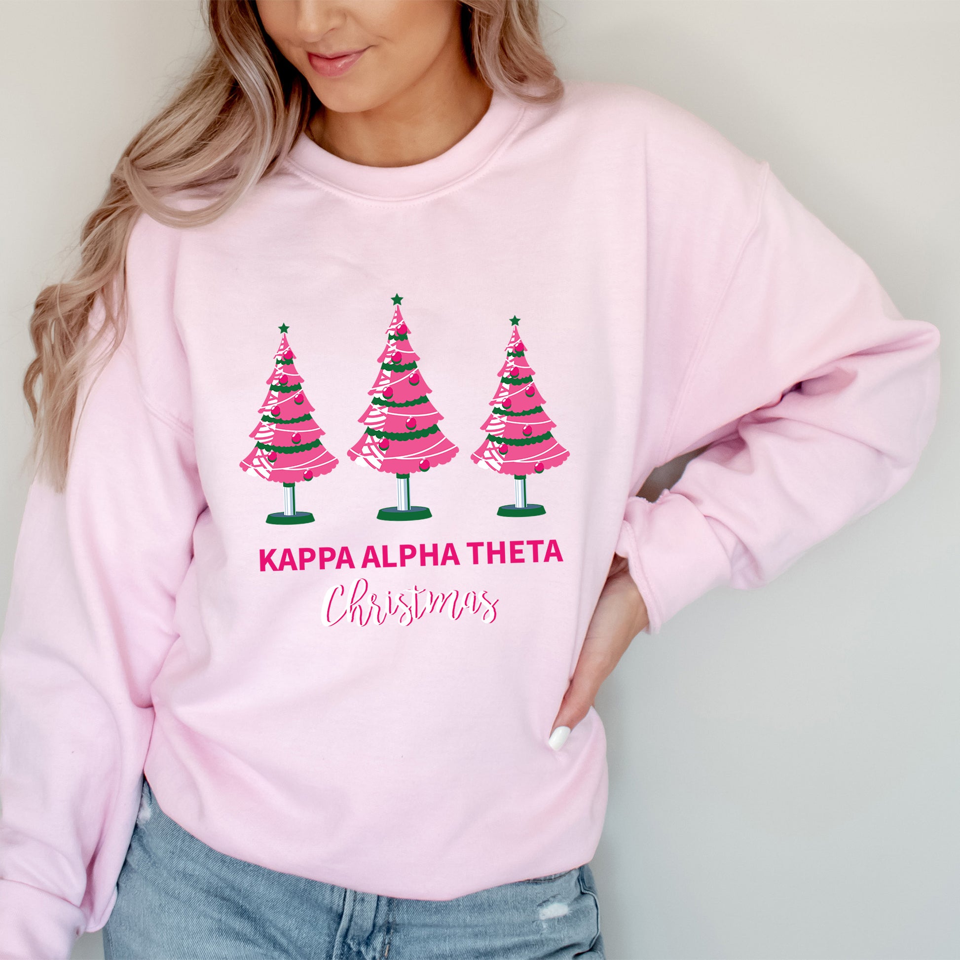a woman wearing a pink sweatshirt with christmas trees on it