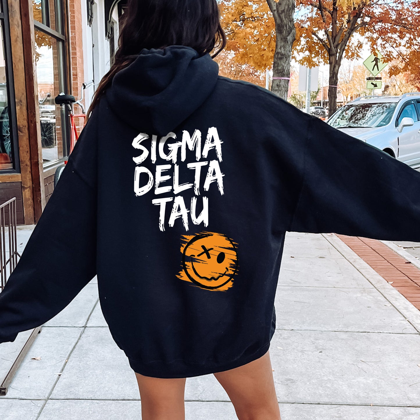 a woman walking down a sidewalk wearing a black sweatshirt