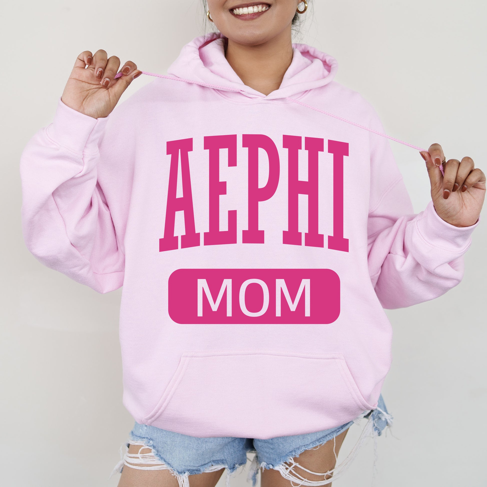 a woman wearing a pink hoodie that says aephi mom