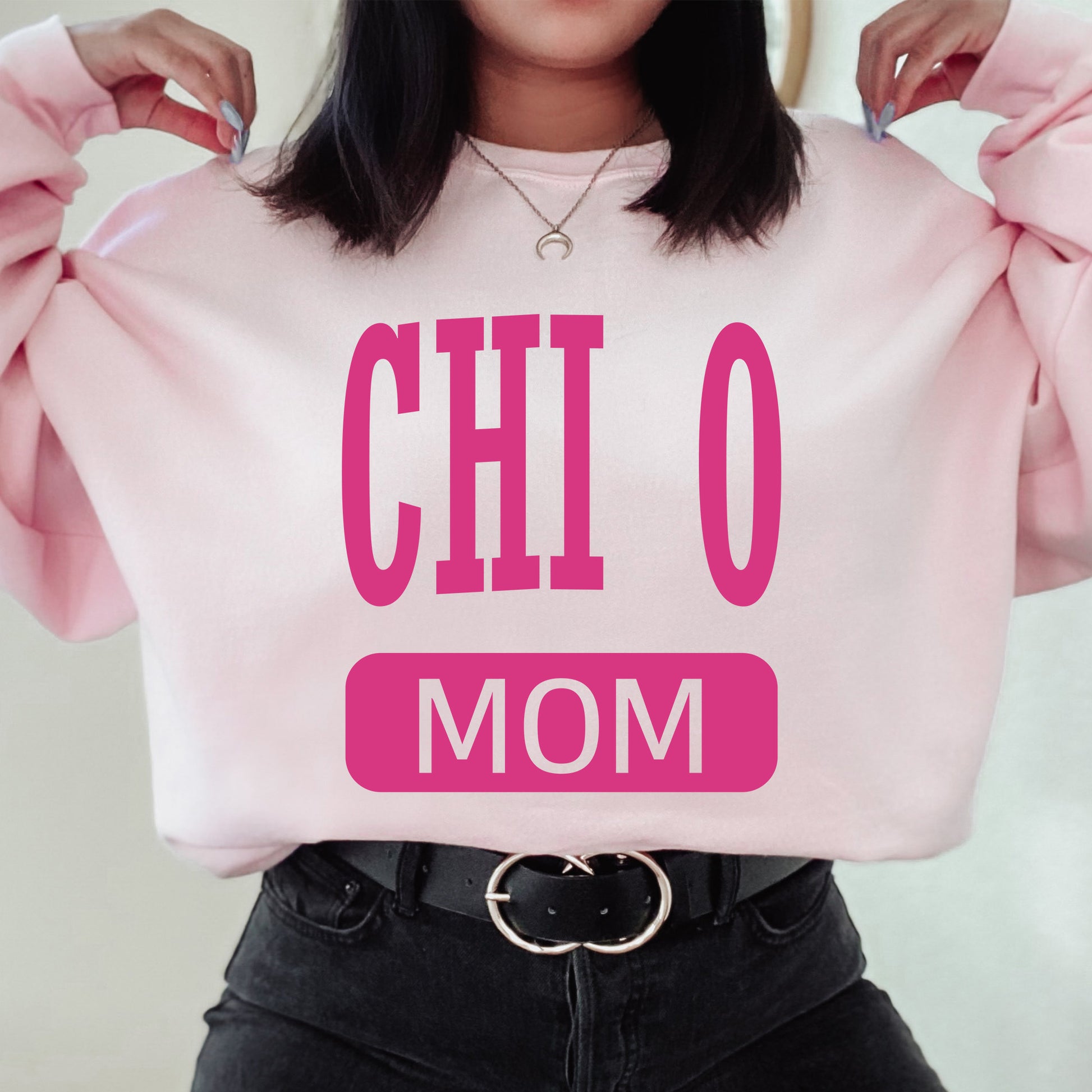 a woman holding a pink sweatshirt that says chio mom