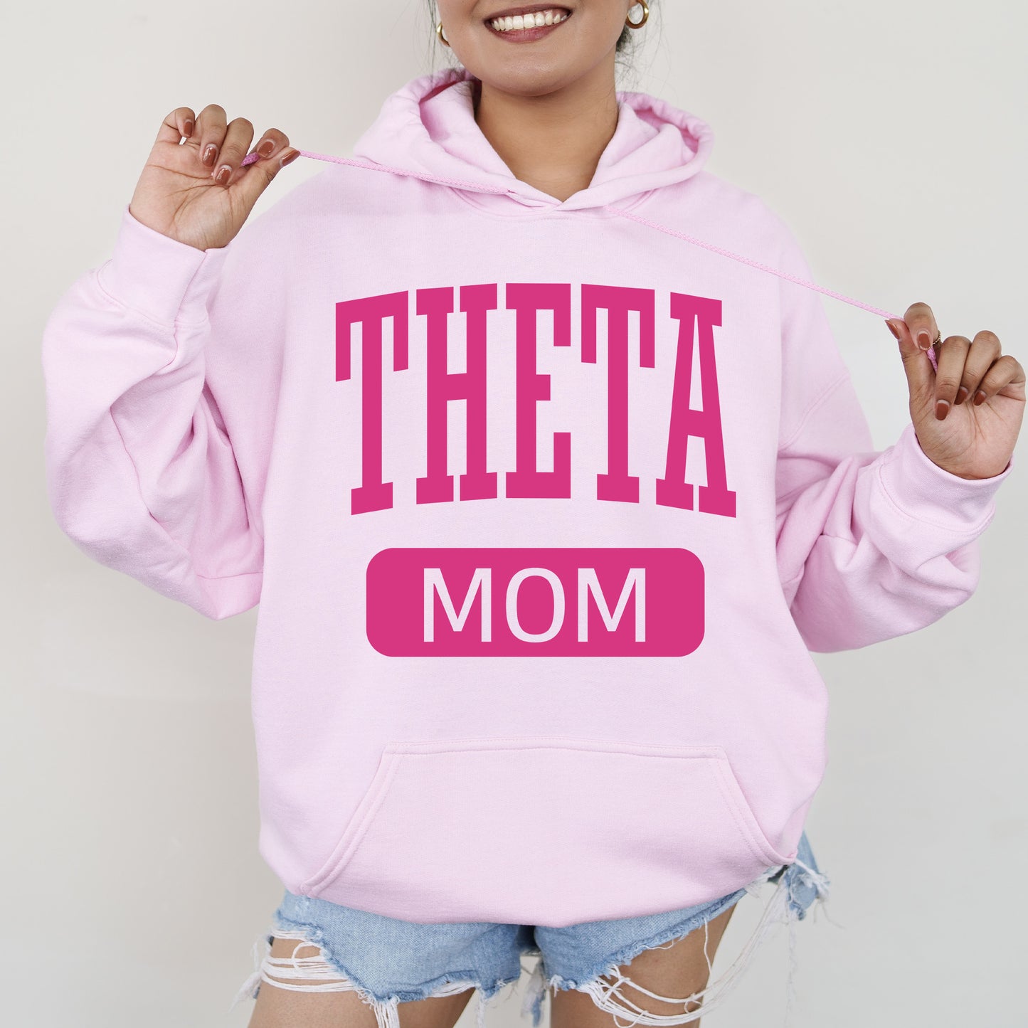 a woman in a pink hoodie that says,'theta mom '
