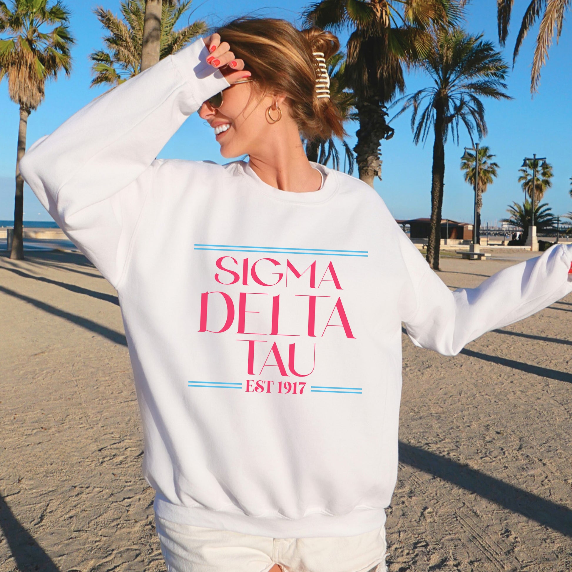 a woman standing on a beach wearing a white sweatshirt