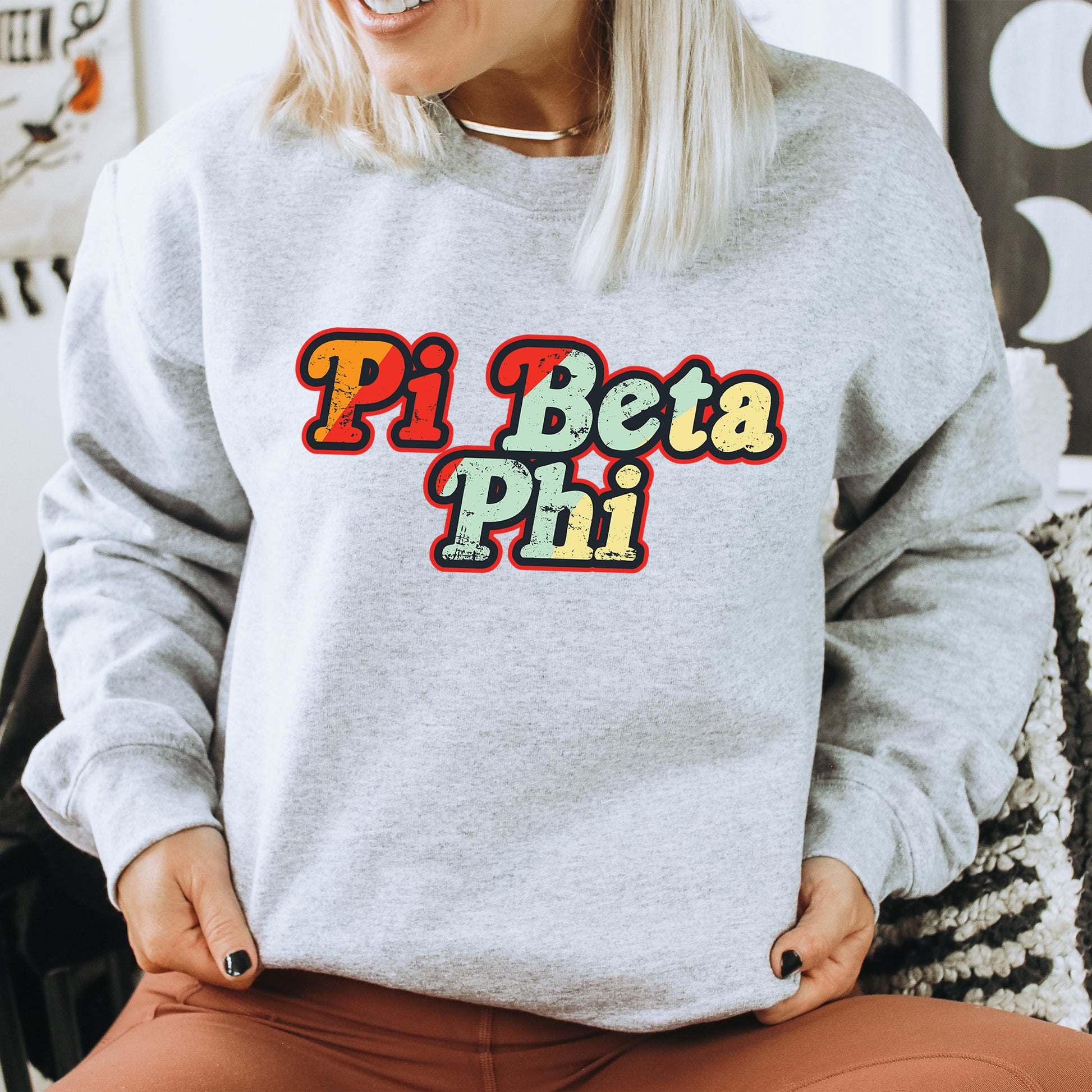 a woman sitting on a chair wearing a sweatshirt that says pi beta pi