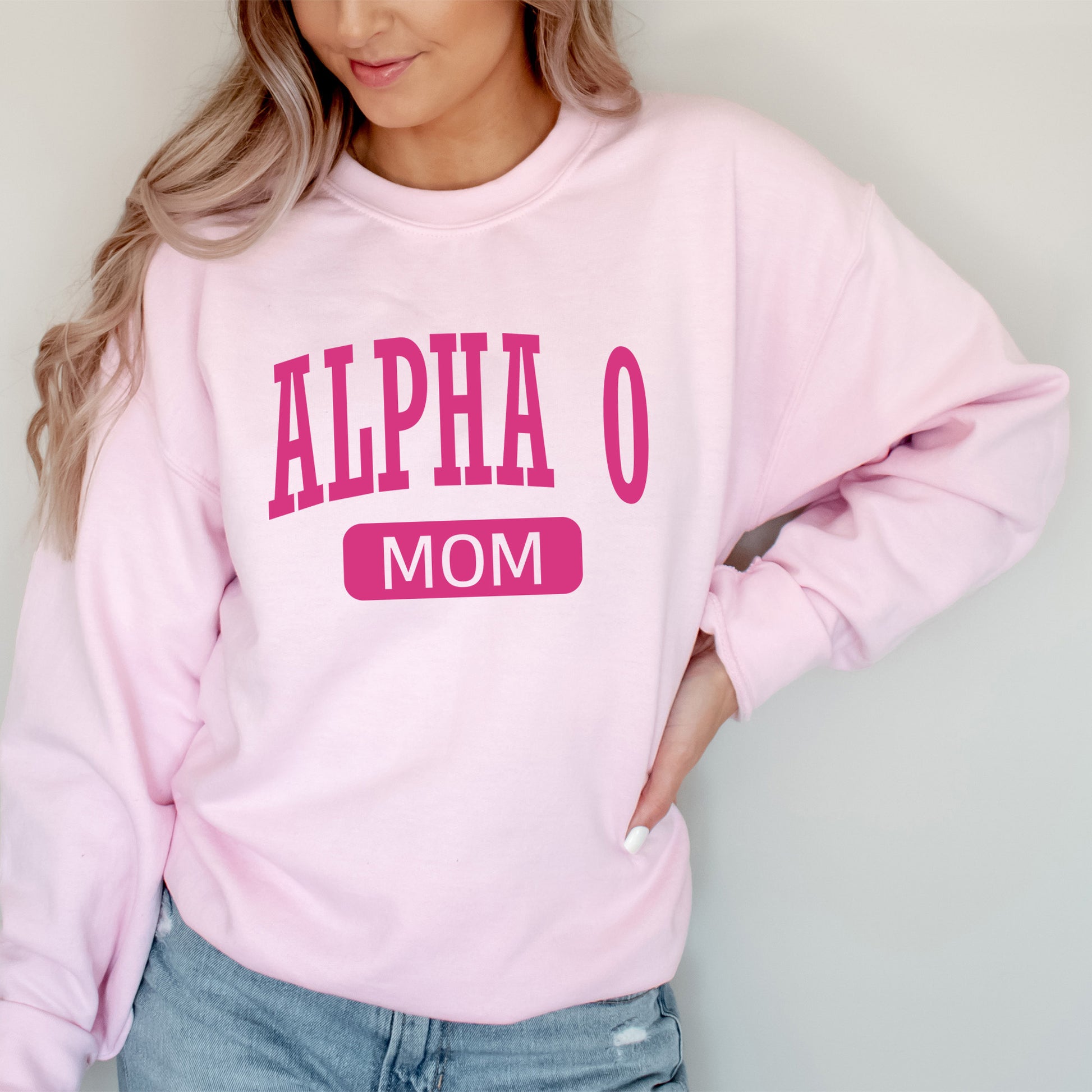 a woman wearing a pink sweatshirt that says,'alpha o mom '