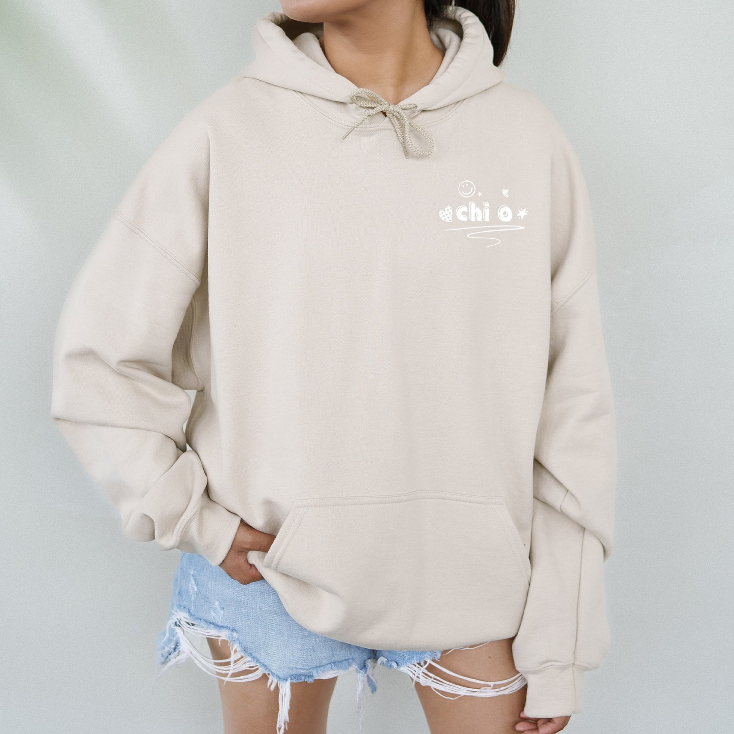 a woman wearing a beige hoodie with a white logo on it