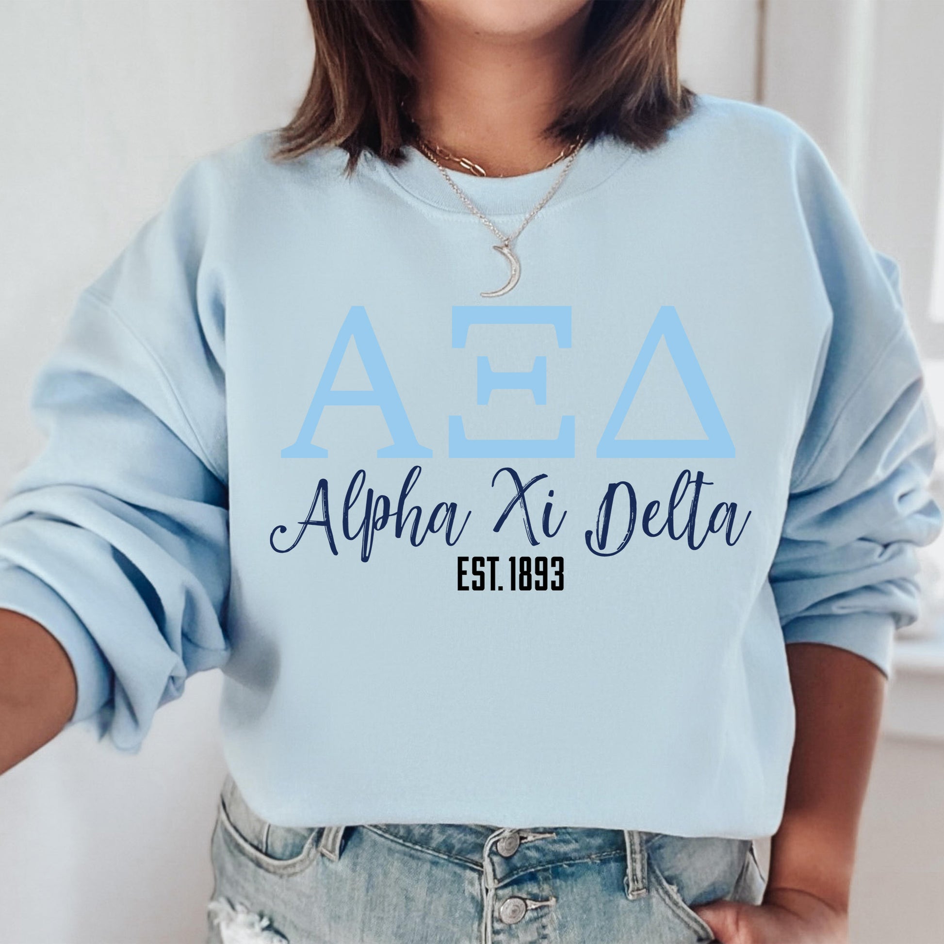 a woman wearing a light blue sweatshirt with the letters apa and delta on it