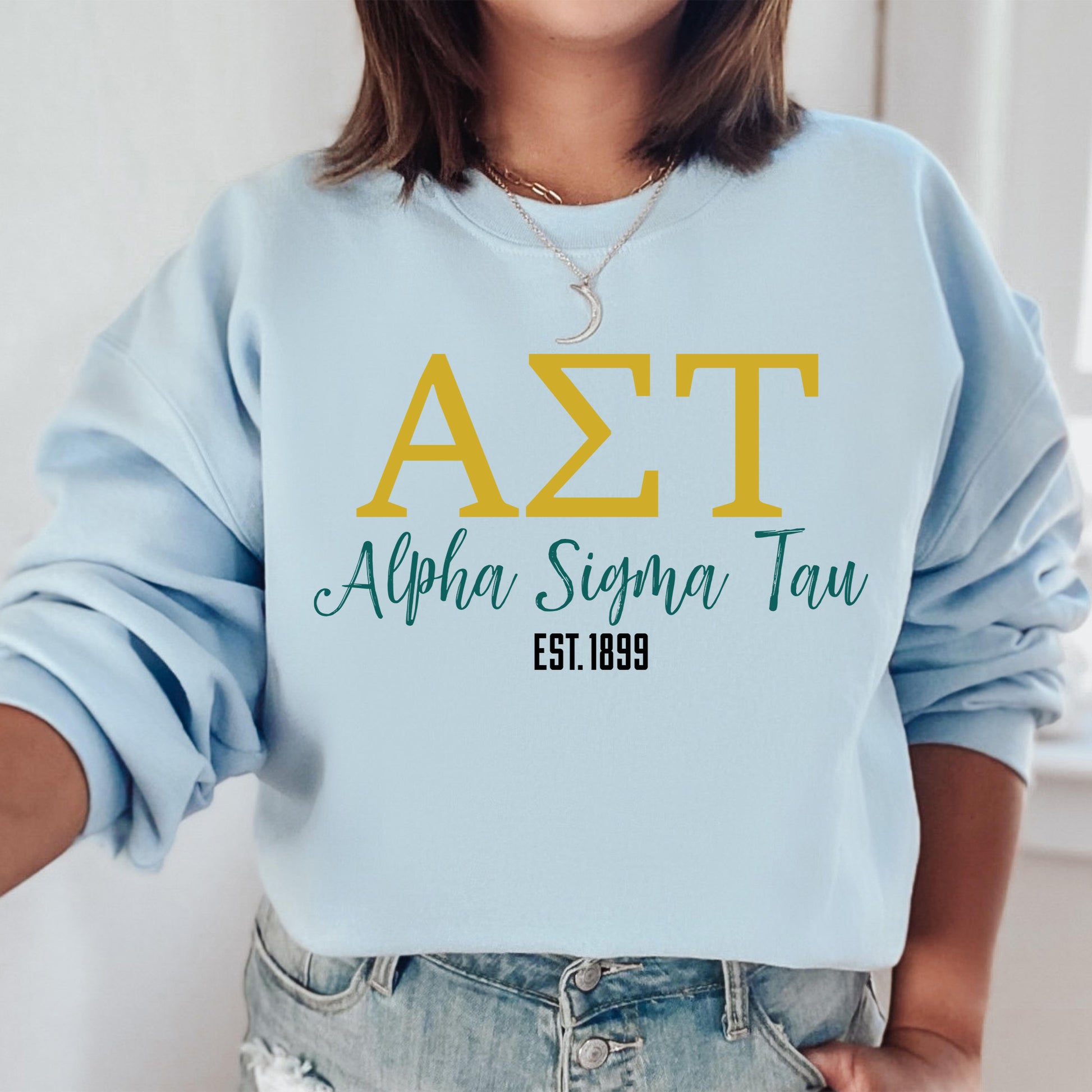 a woman wearing a light blue sweatshirt with the letters azt on it